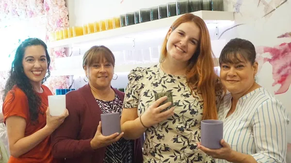 Four women holding the candles they made at a Wick & Pour class in New York City