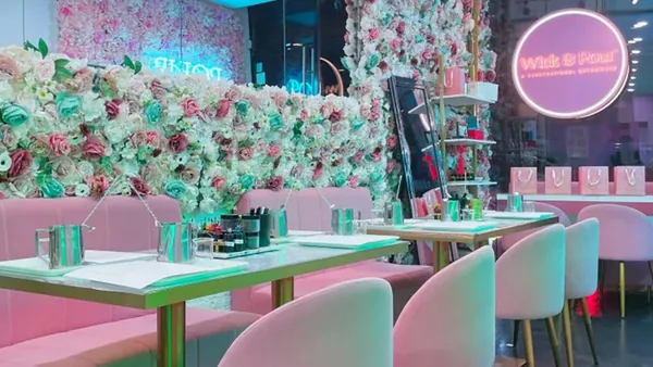 Wick & Pour NoLita studio with a floral wall, pink chairs and candle making tables