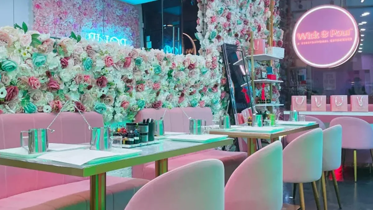 Wick & Pour NoLita studio with a floral wall, pink chairs and candle making tables
