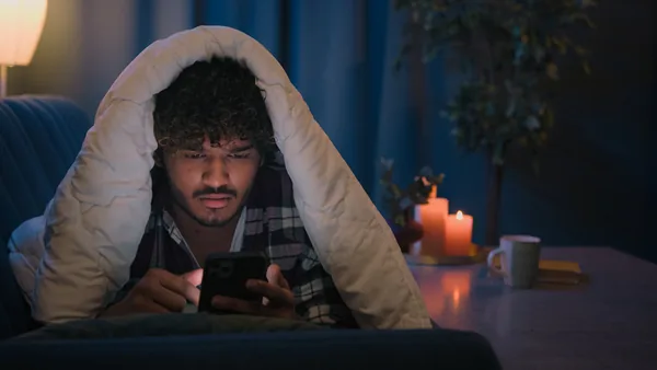Person wrapped in a blanket reading by candlelight at home