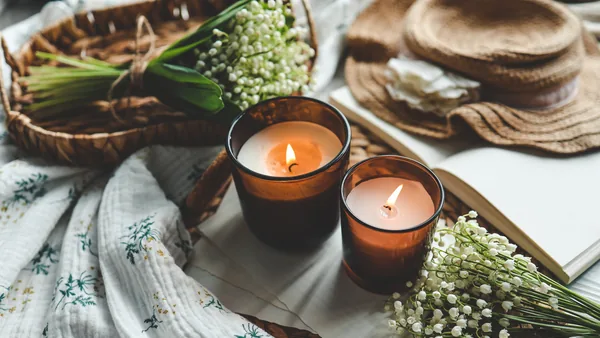 Two lit candles on a tray with lily of the valley flowers