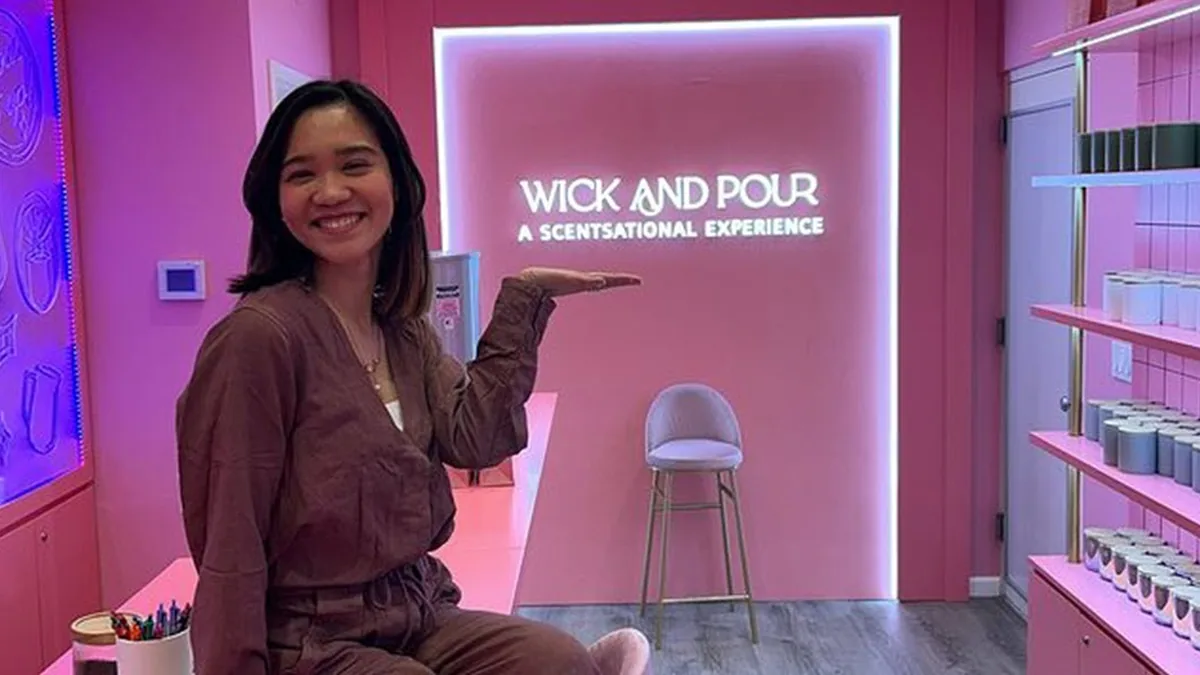 Guest posing by the neon Wick and Pour sign in the West Village studio