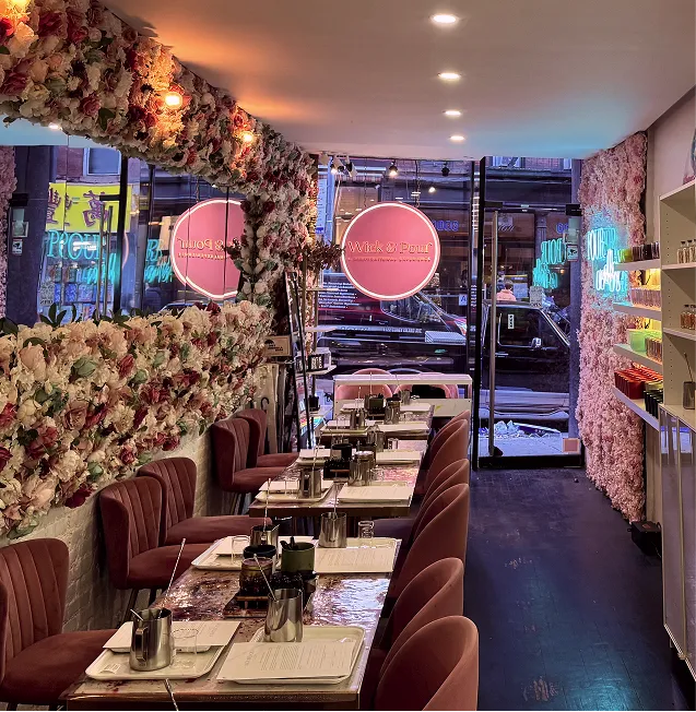 Wick & Pour NoLita studio on Mott Street, with floral walls, velvet booths, and tables set for a candle making class
