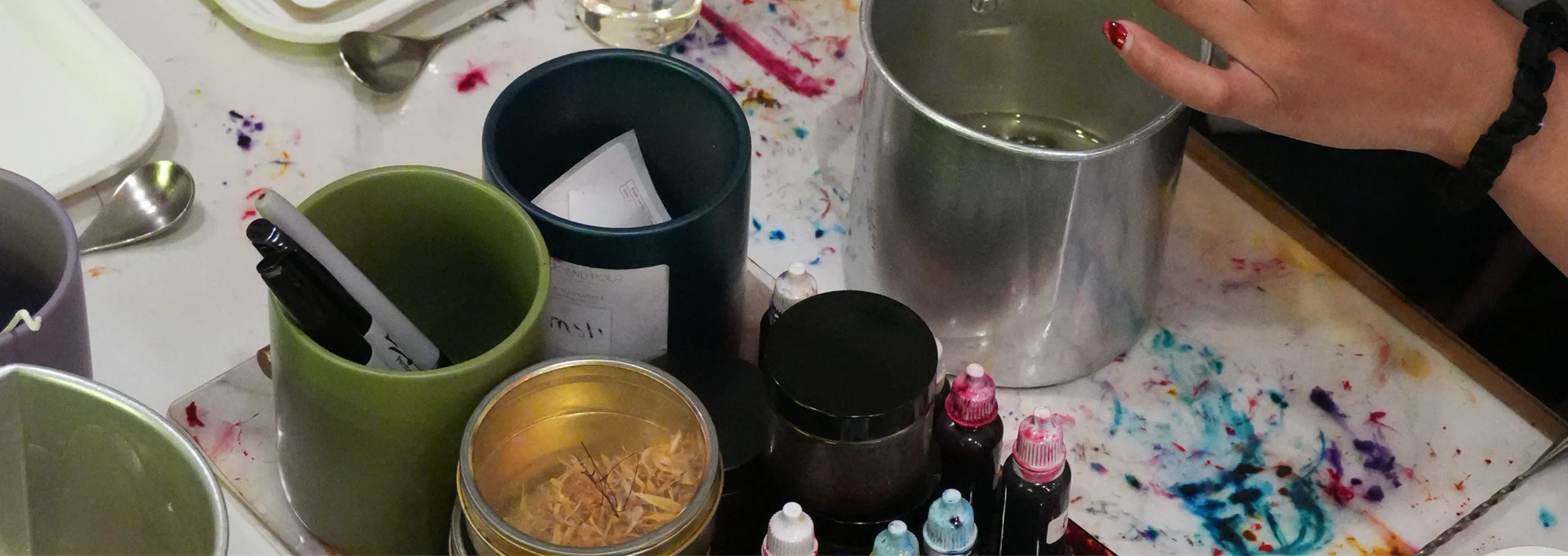 Wick & Pour candle making station at an event, with a wax pitcher, fragrance droppers, vessels, and dried botanicals