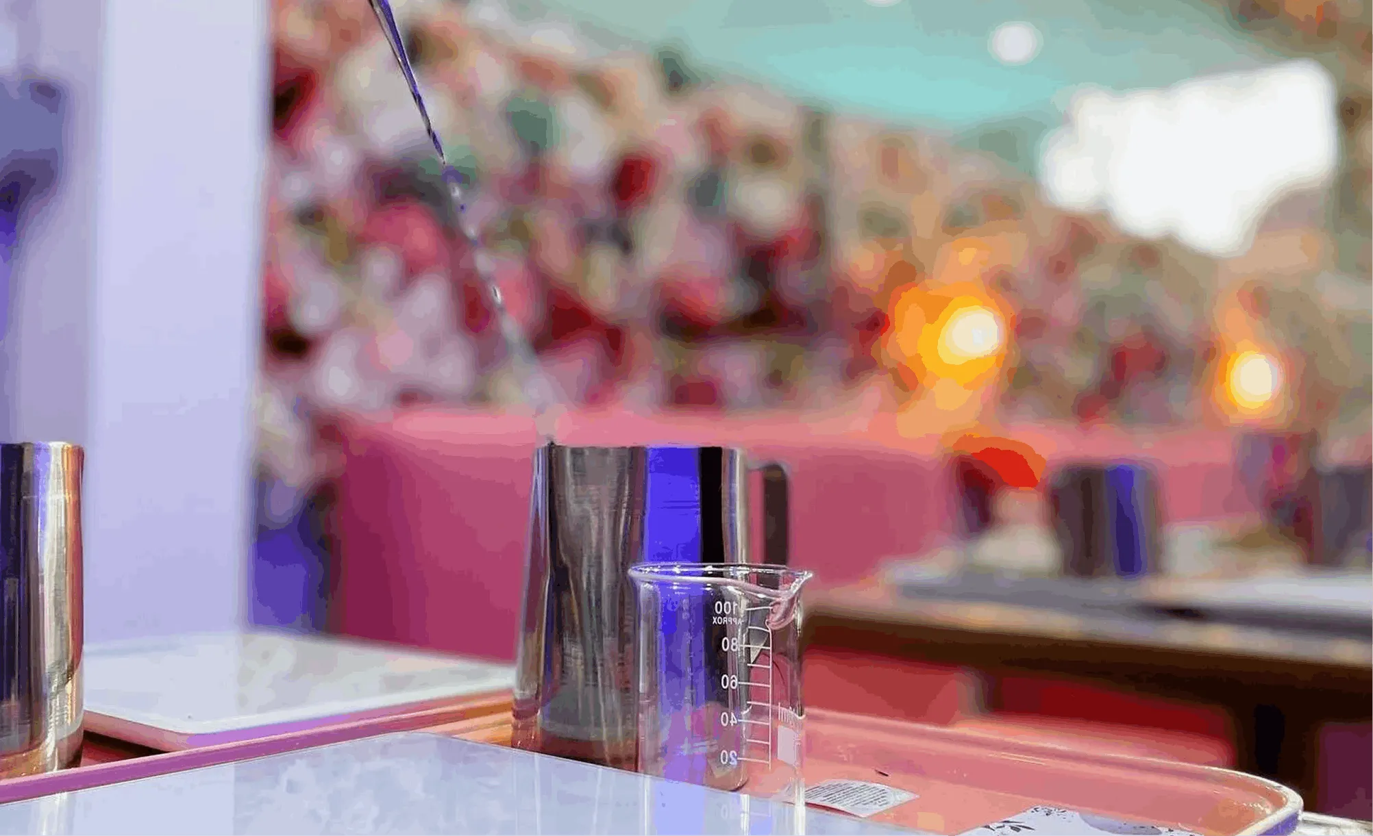 Candle making station with a pouring pitcher in front of Wick & Pour's flower wall