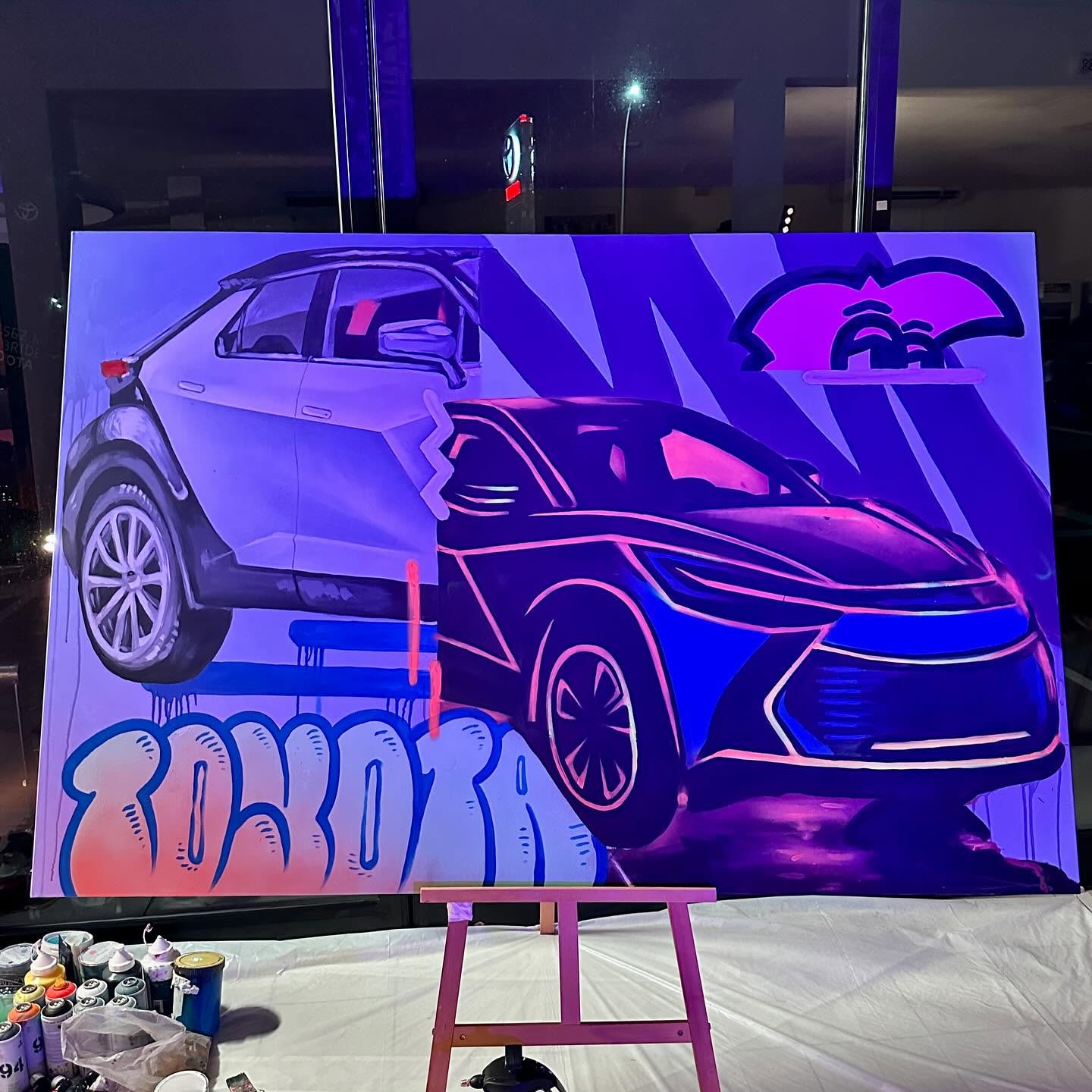 Toile du Toyota C-HR peinte par Hugo W2CJ, sur un chevalet, éclairée à la lumière noire