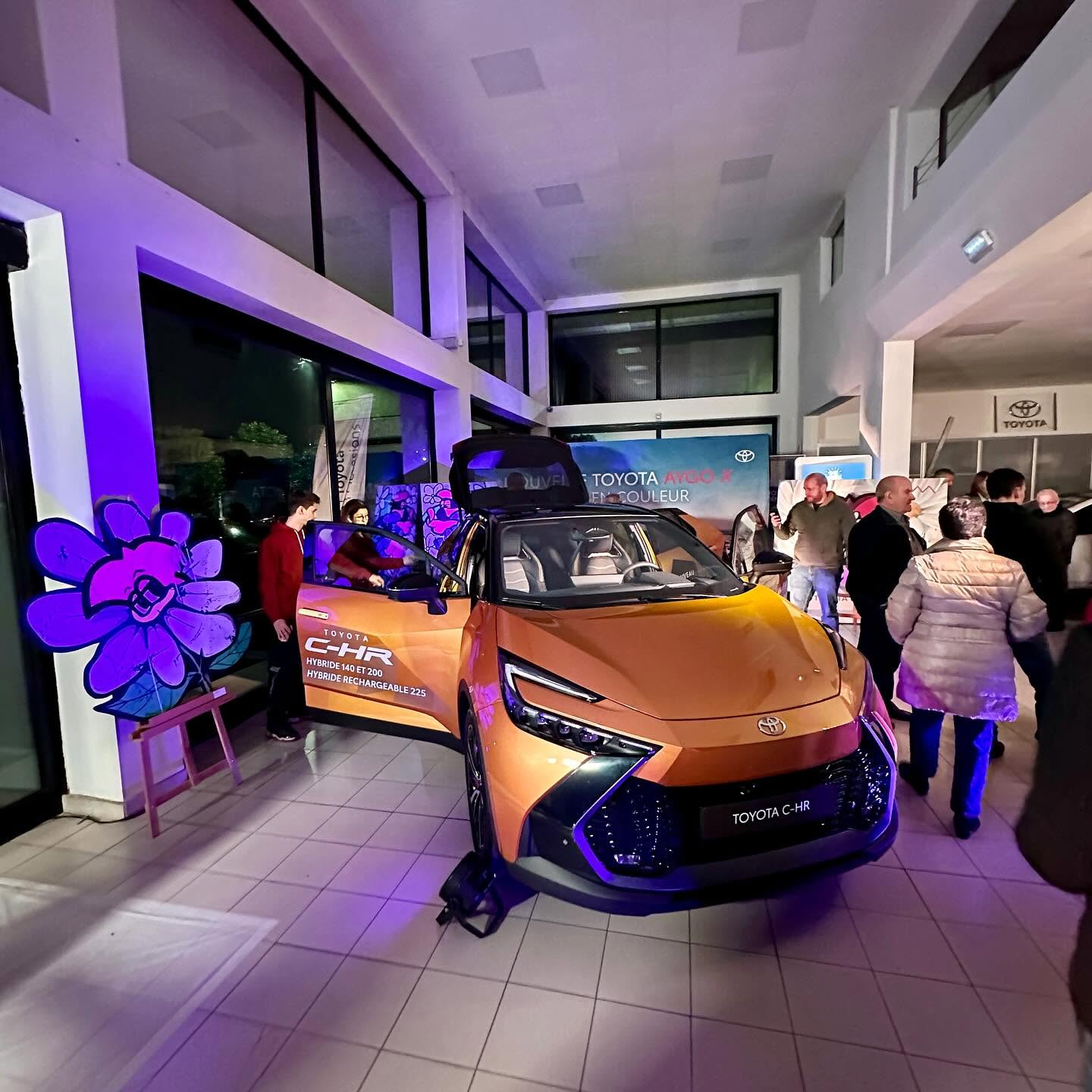 Le nouveau Toyota C-HR orange dévoilé devant le public, entouré des pièces découpées de Hugo W2CJ