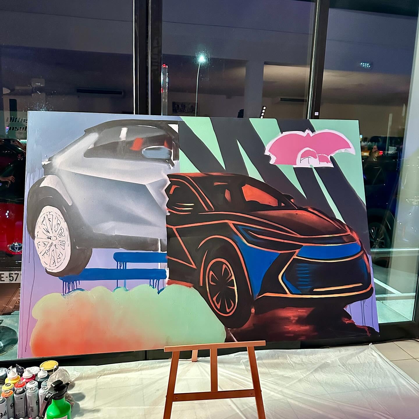 Toile du Toyota C-HR en cours, le modèle de profil et de face, devant la vitrine de la concession