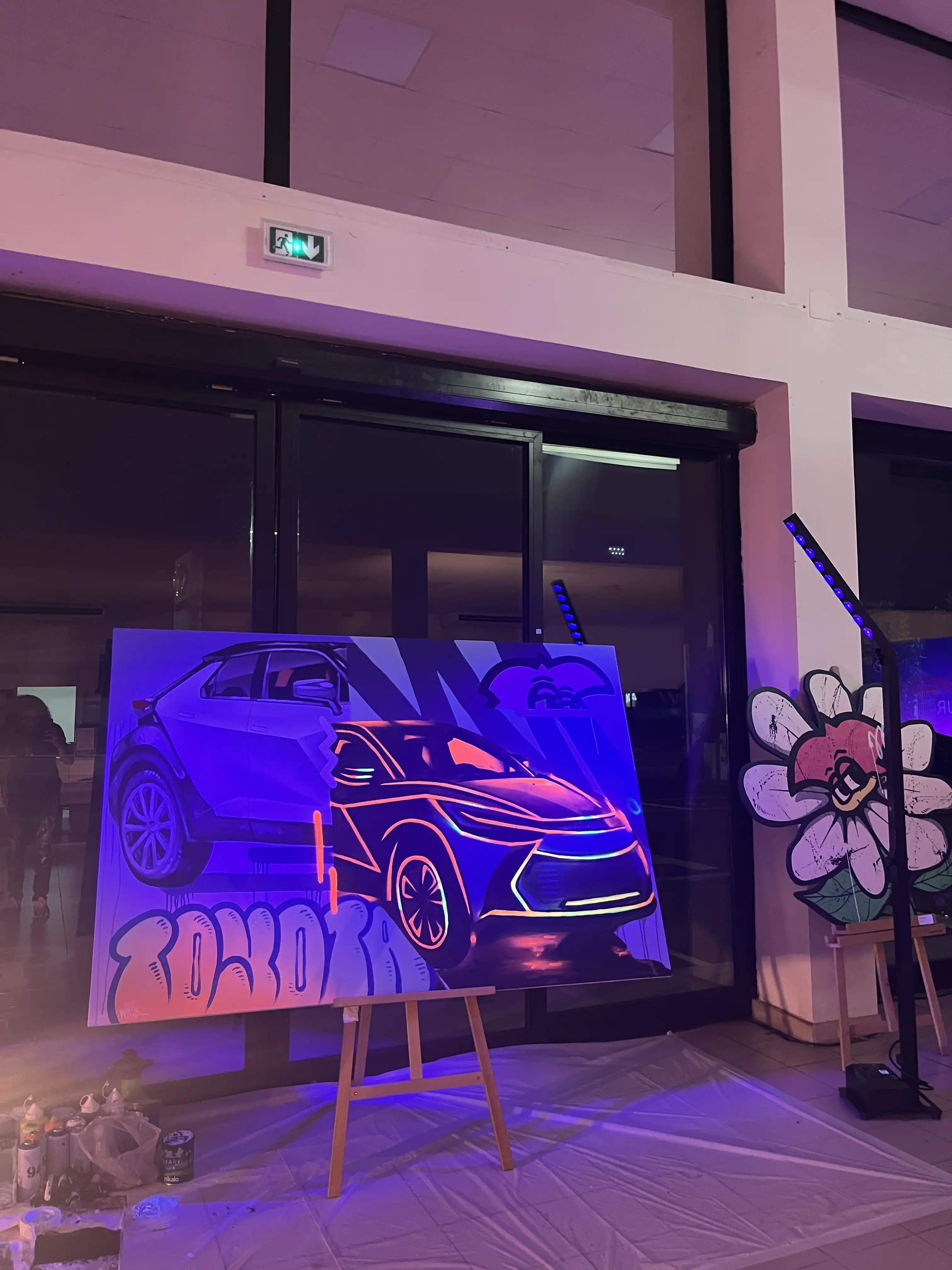 La toile du C-HR sous lumière noire, avec le lettrage Toyota en graffiti et les bombes de peinture au sol