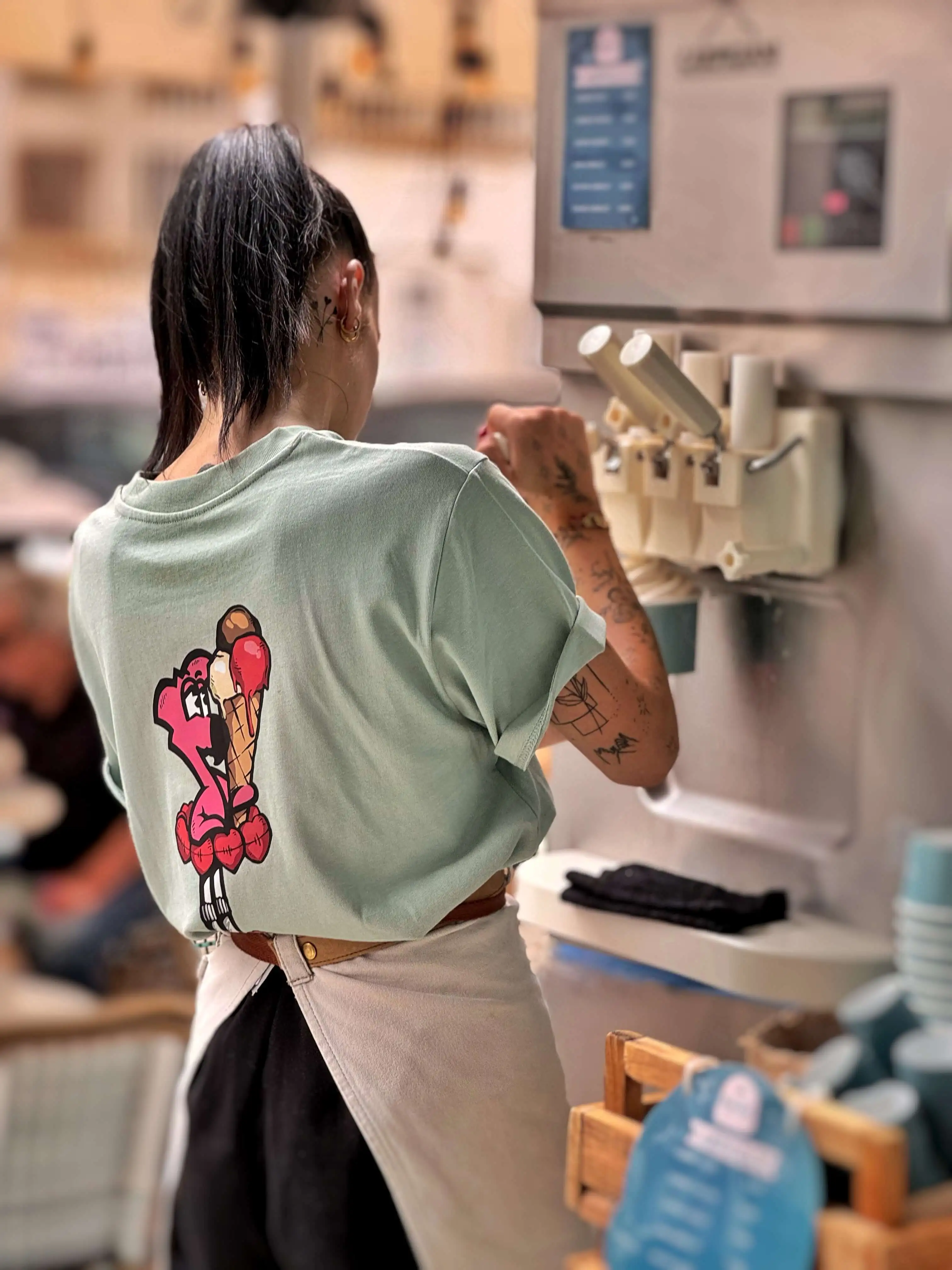 T-shirt vert d'eau du staff Raugi, avec Roger le Flamant Rose et son cornet dessinés par Hugo W2CJ, porté derrière le comptoir