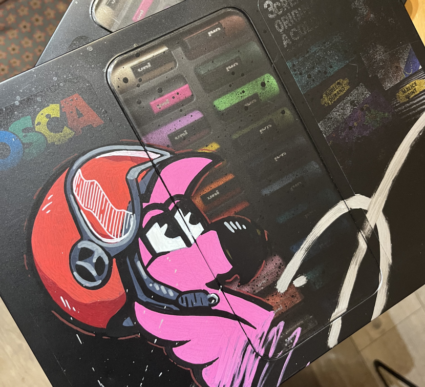 Mallette Posca customisée d'un flamant rose casqué en moto, devant un casque rouge