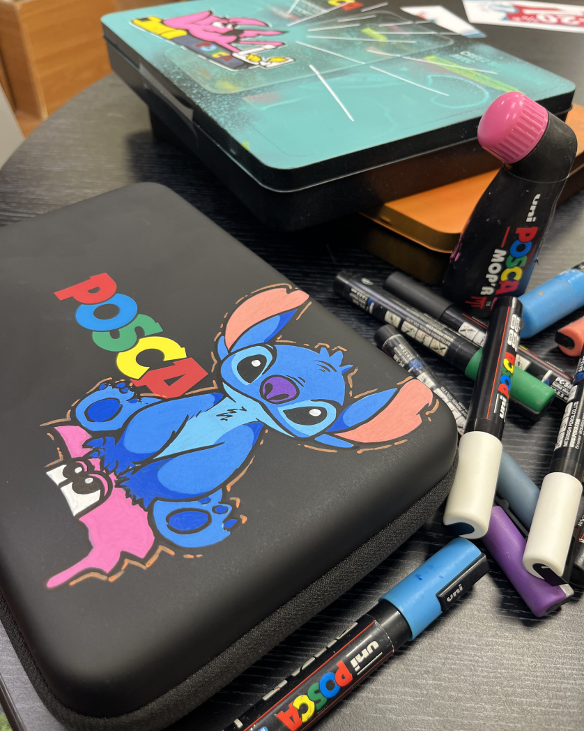Mallette Posca noire customisée à la demande d'un client : personnage bleu et flamant rose, entourée de marqueurs