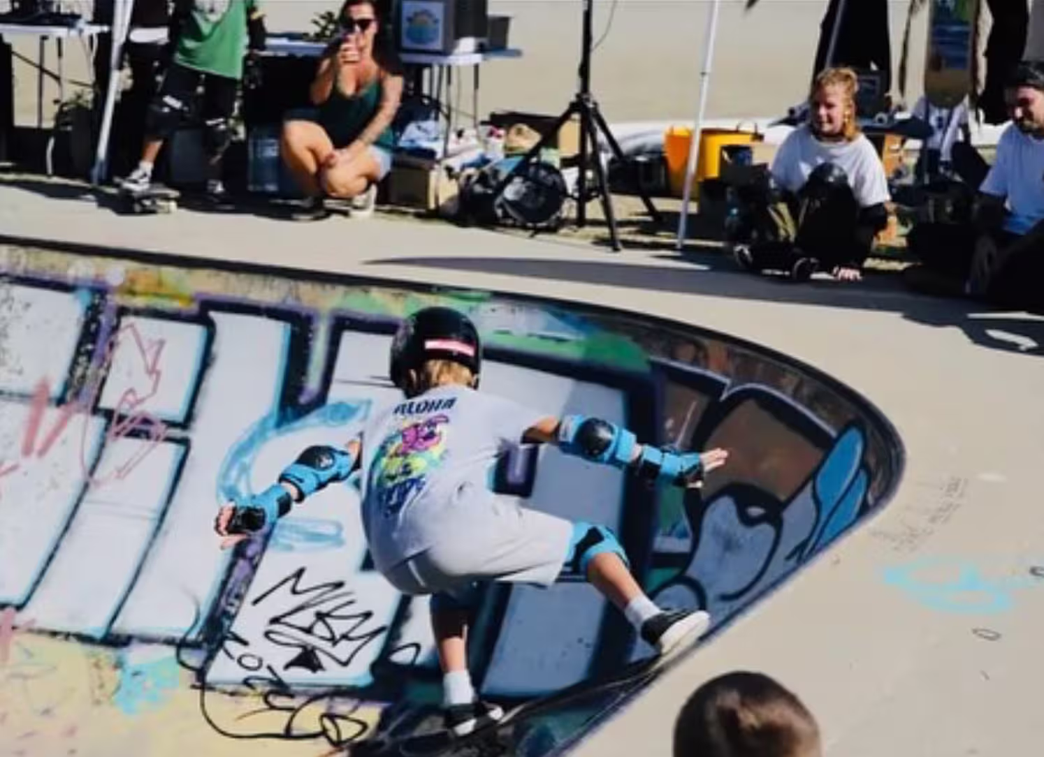 Skateur en action dans le bowl graffé de l'Arinella pendant l'Aloha Skate Cup, devant le public