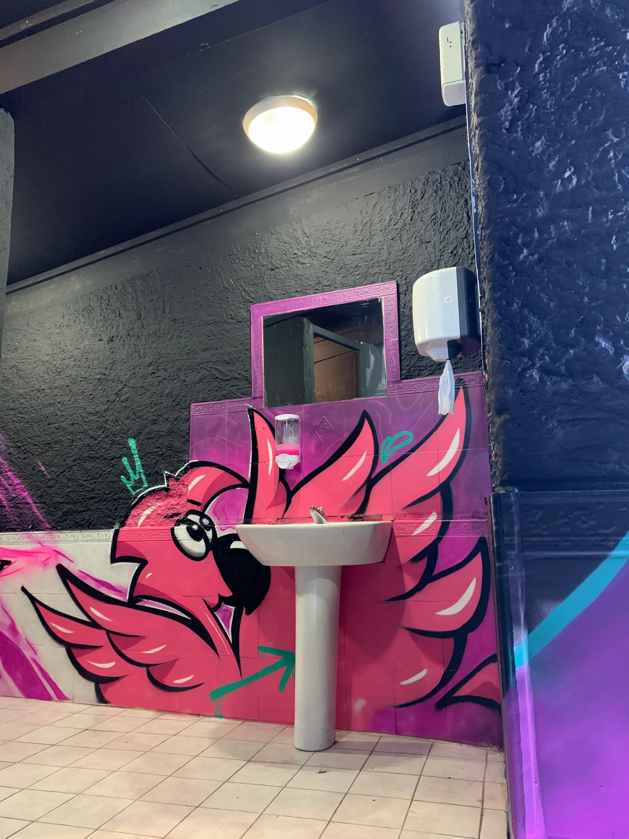 Flamant rose peint autour du lavabo des sanitaires de La Conca, sur fond violet, 2020