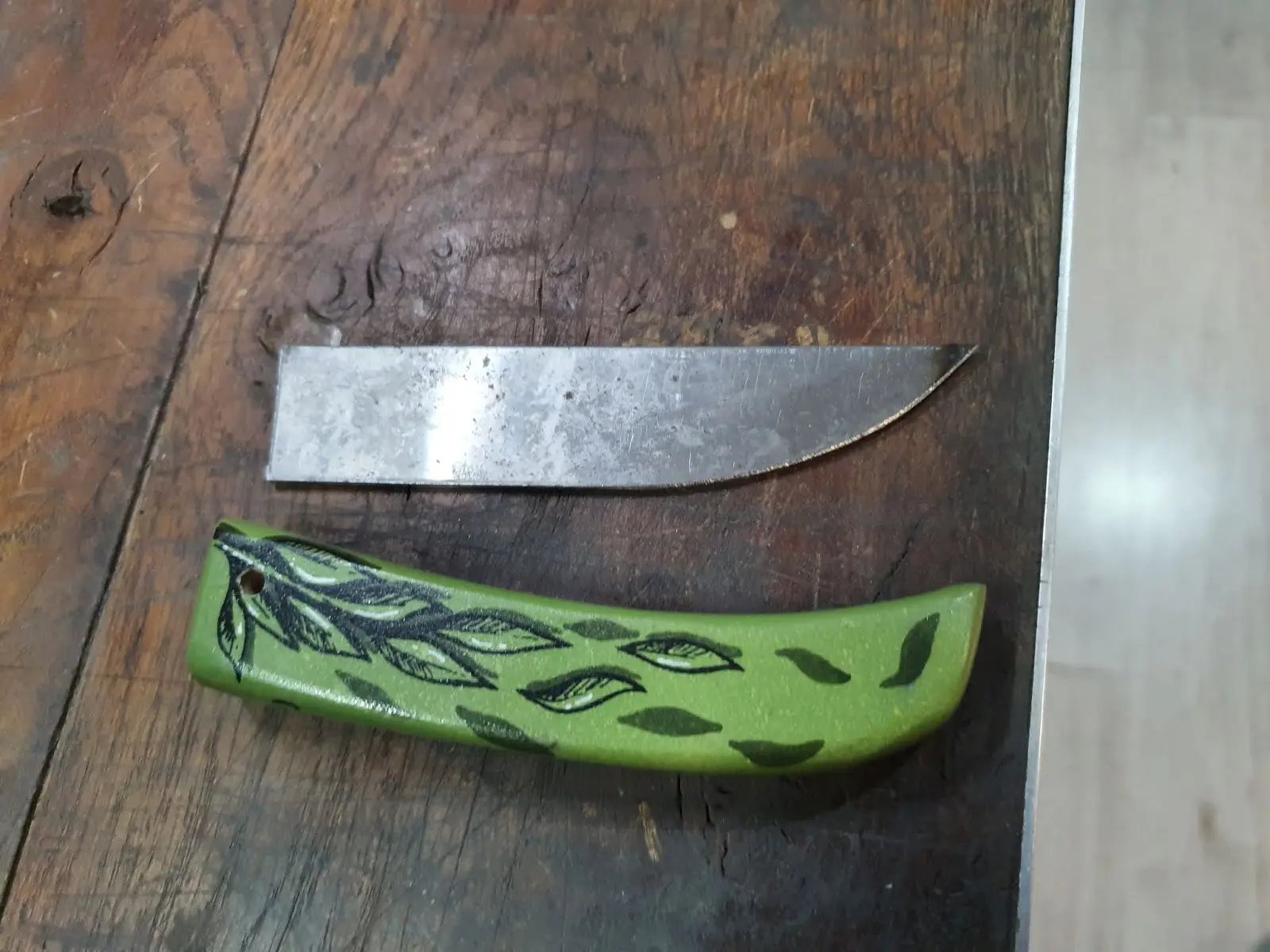 Manche vert peint par Hugo W2CJ d'un feuillage noir, posé à côté de sa lame avant le montage du couteau