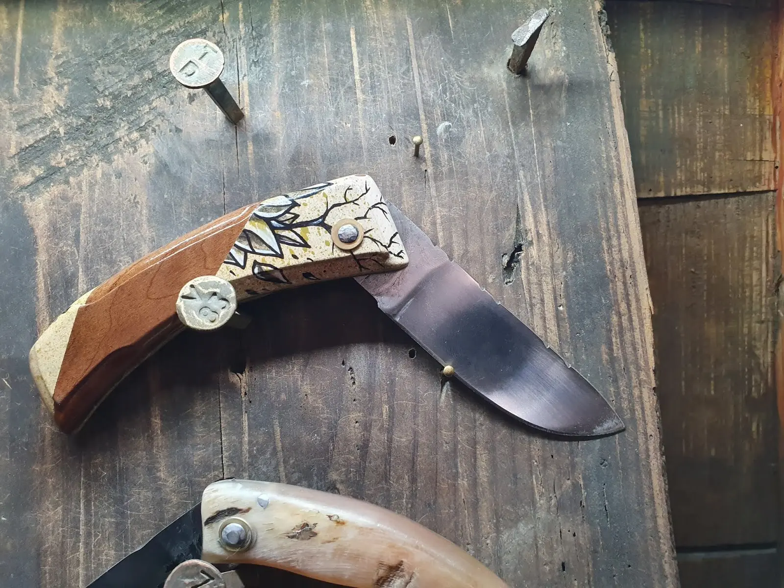 Couteau pliant de Manu Padovani au manche en bois, dont la partie claire est peinte de motifs noirs par Hugo W2CJ