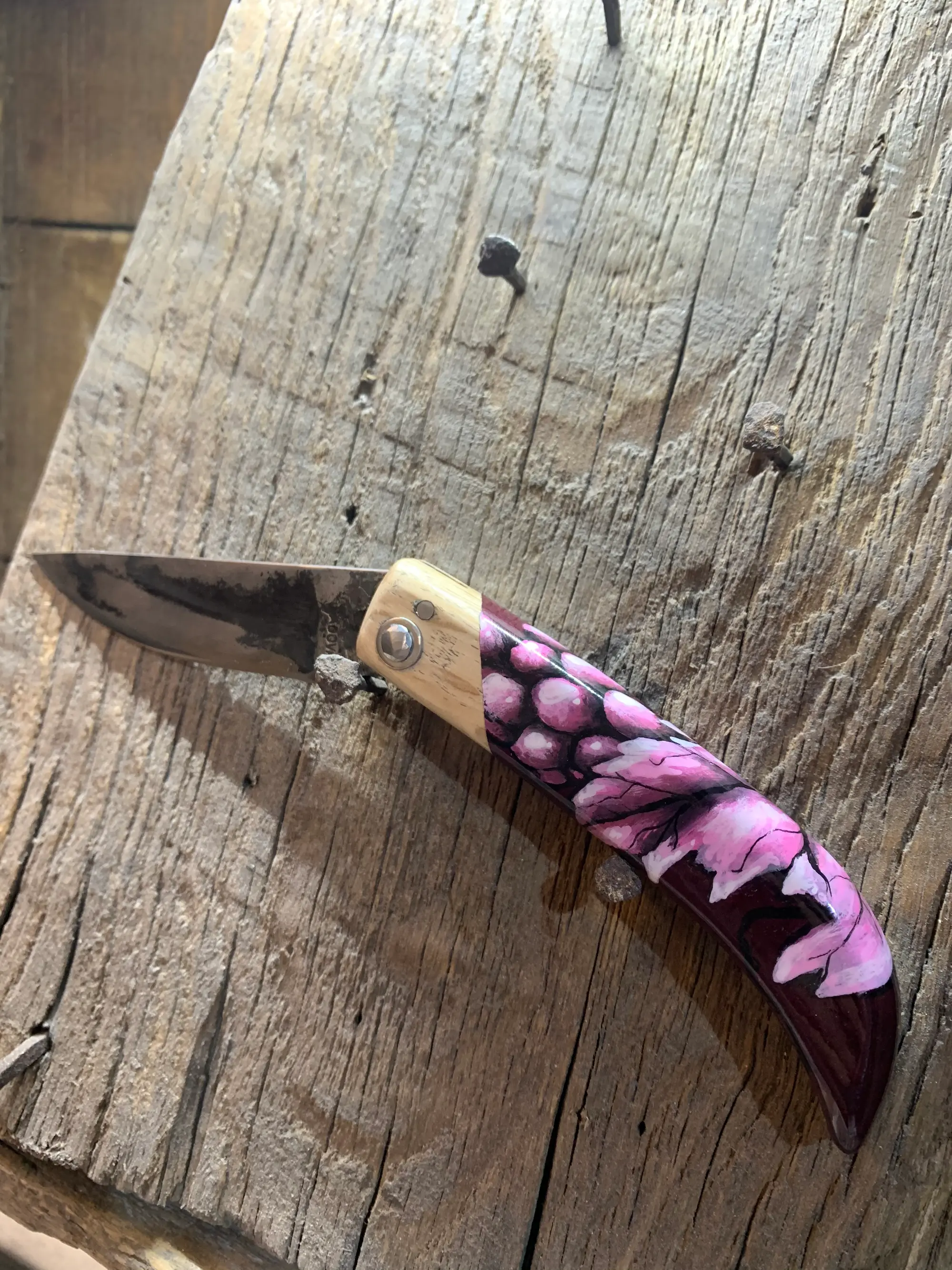 Couteau pliant de Manu Padovani au manche peint par Hugo W2CJ d'une grappe de raisin rose et de feuilles de vigne
