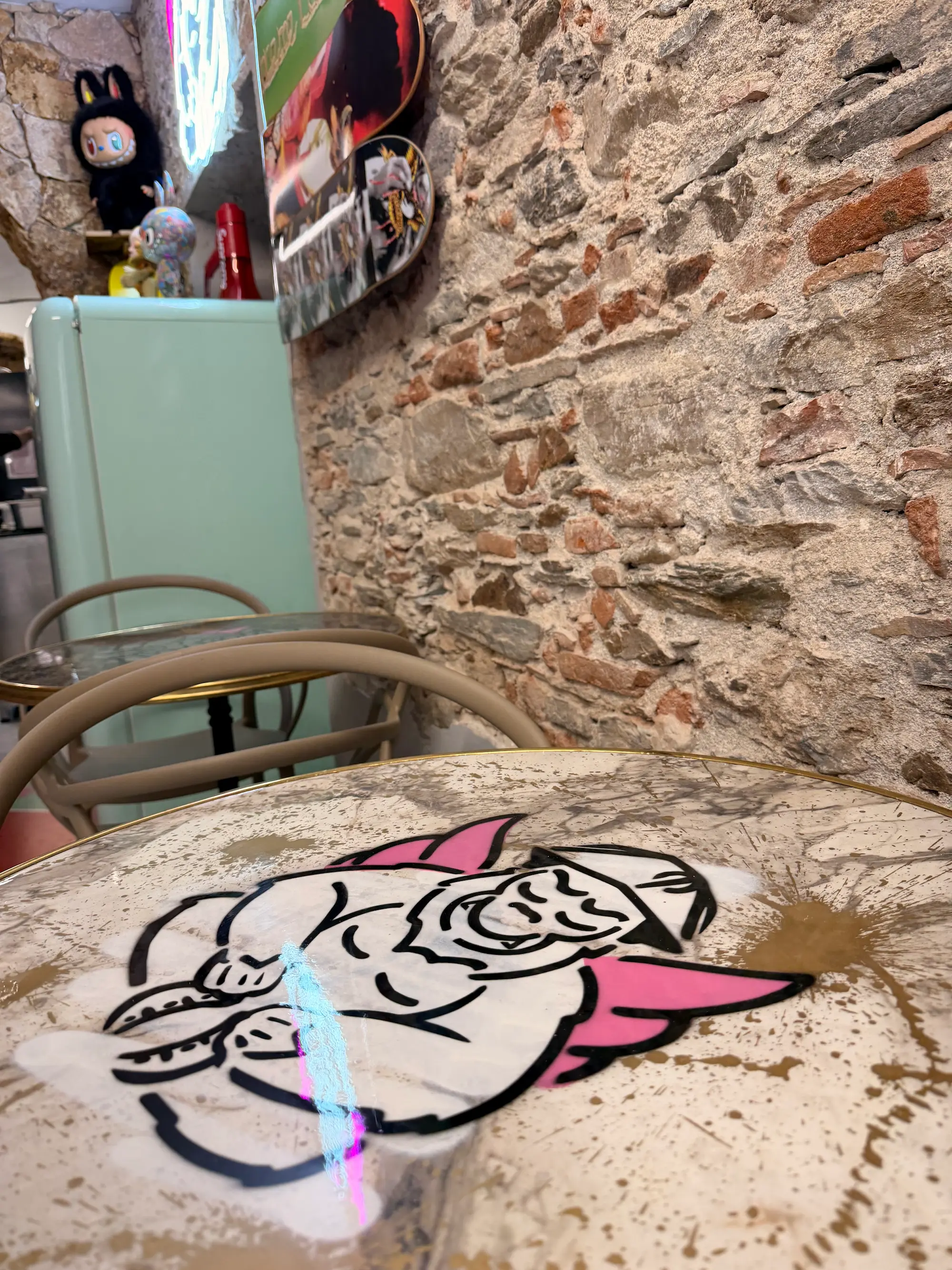 Table de Chez Jean marquée de la mascotte ailée dessinée par Hugo W2CJ, devant un mur en pierre
