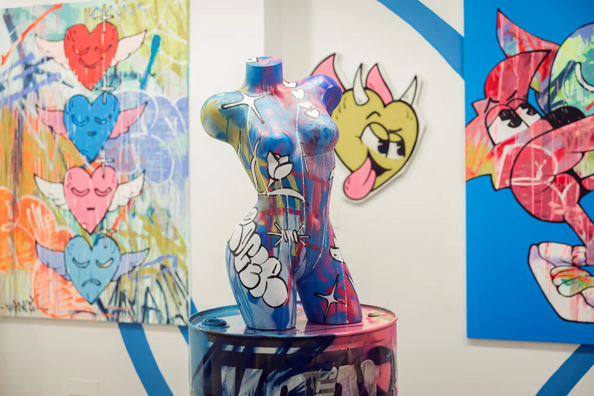 Buste peint devant des toiles aux cœurs ailés, exposition Cœur Bleu de Hugo W2CJ