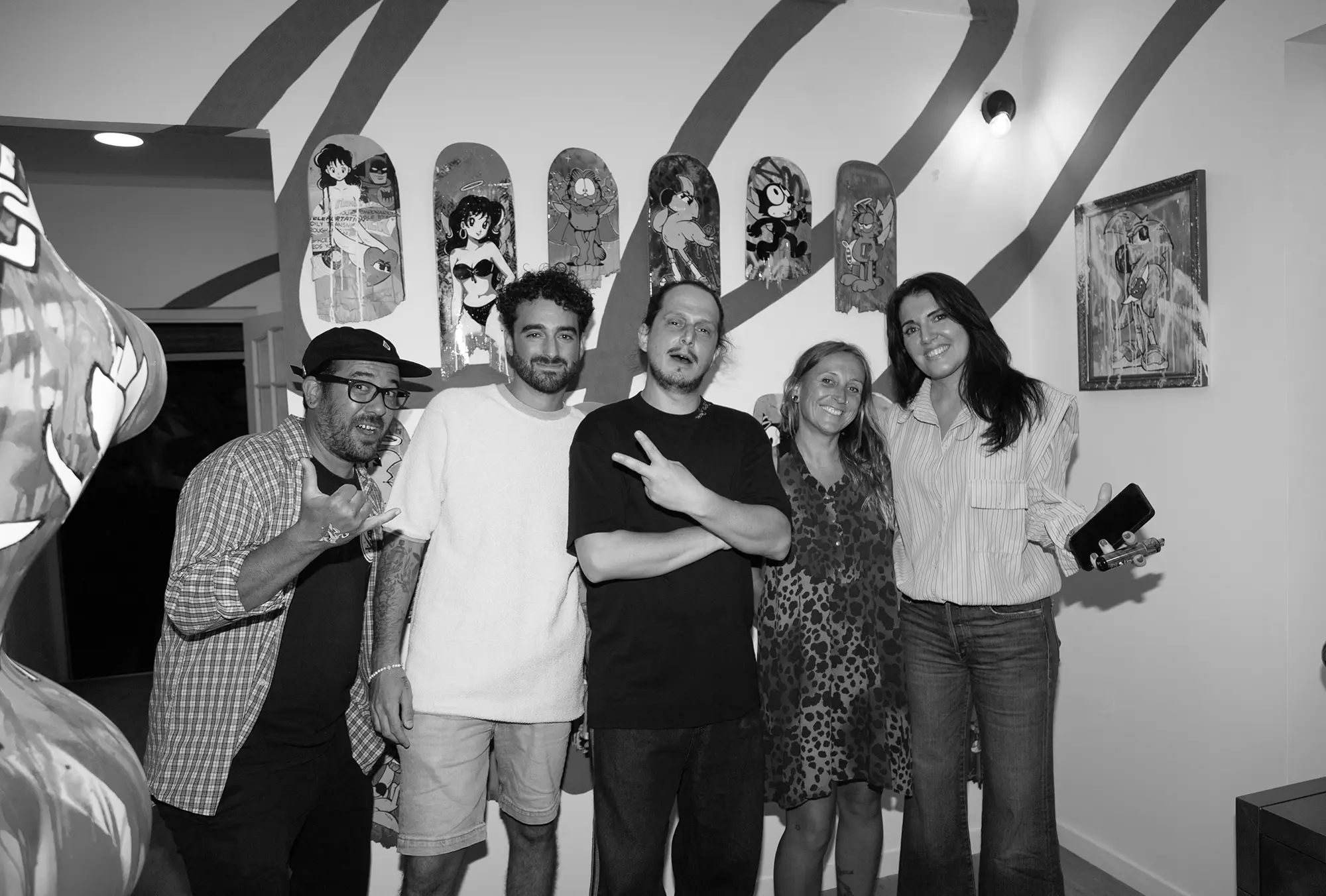 Hugo W2CJ entouré de proches devant le mur de planches de skate, soir du vernissage de Cœur Bleu, photo en noir et blanc