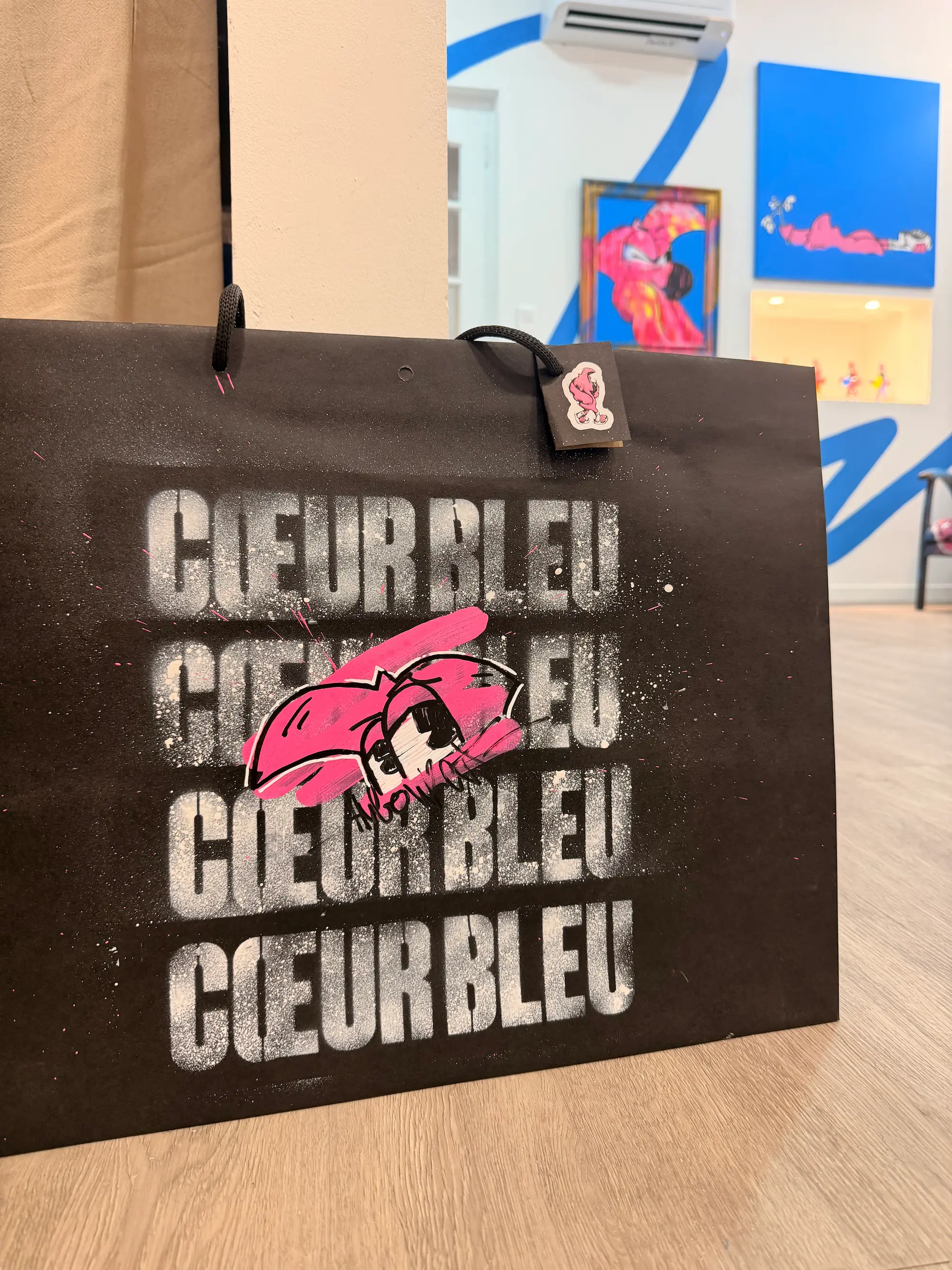 Sac noir customisé au pochoir Cœur Bleu, avec Roger peint en rose, dans la galerie