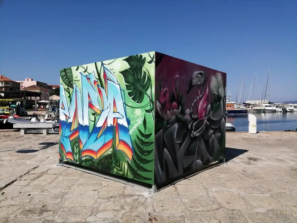 Live painting collectif au chapiteau Artpoval, 2019 : cube peint sur le port, lettrage graffiti arc-en-ciel sur une face et flamant squelette sur l'autre