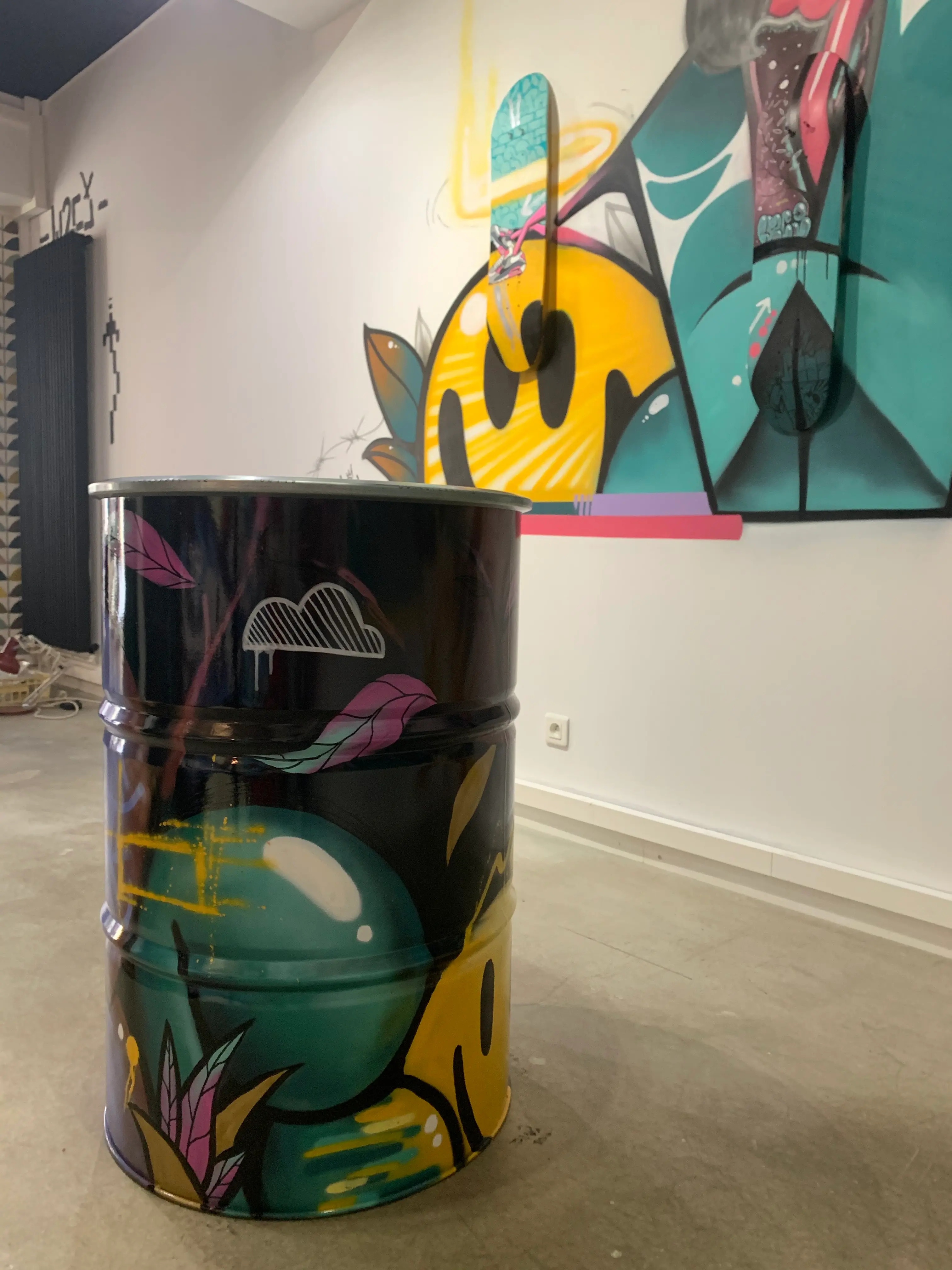 Exposition collective à La Conciergerie de Metz, 2020 : bidon métallique peint en graffiti devant la fresque murale de la salle
