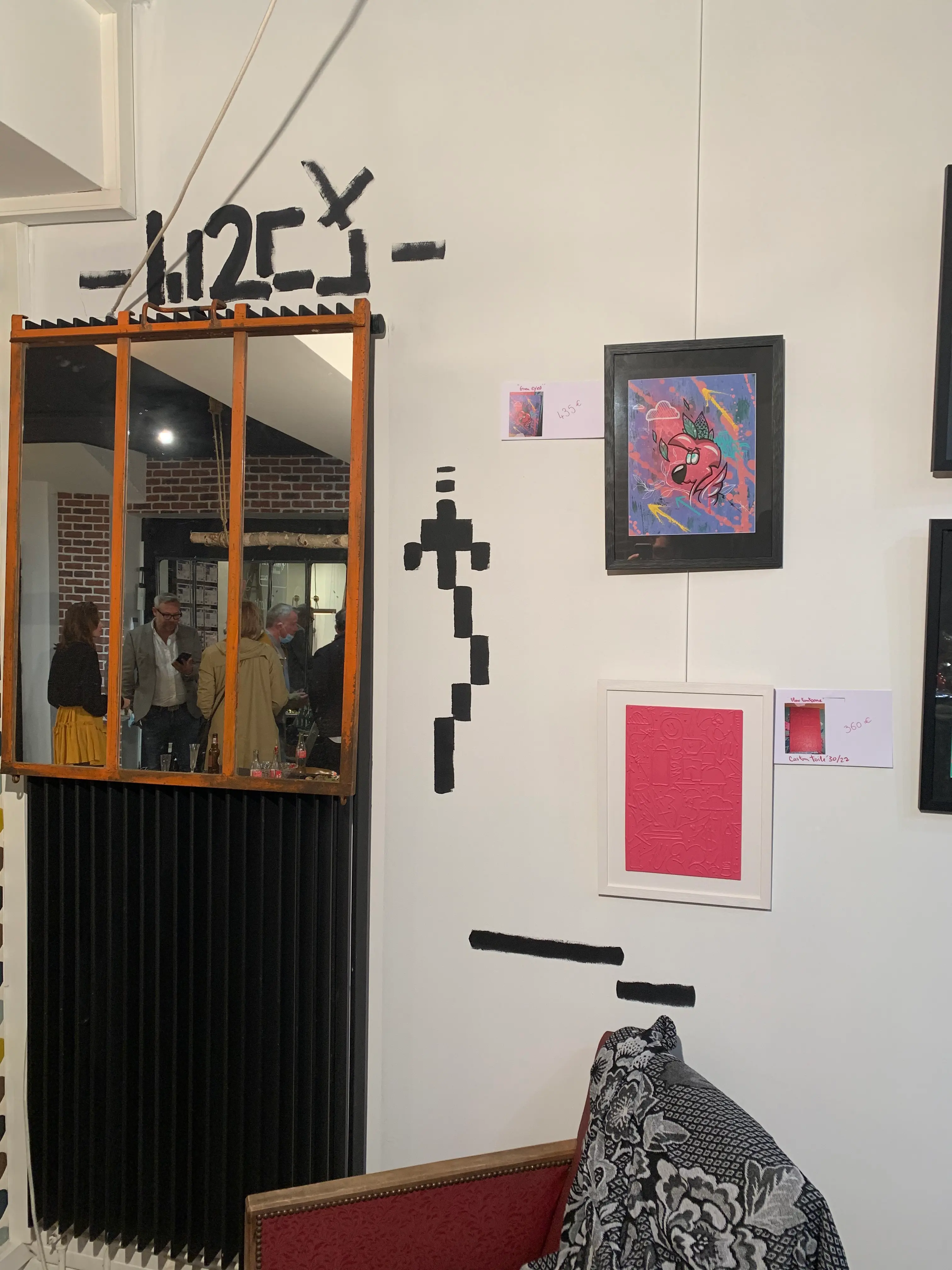 Exposition collective à La Conciergerie de Metz, 2020 : accrochage d'œuvres encadrées sur un mur blanc, signature W2CJ peinte au-dessus d'un miroir