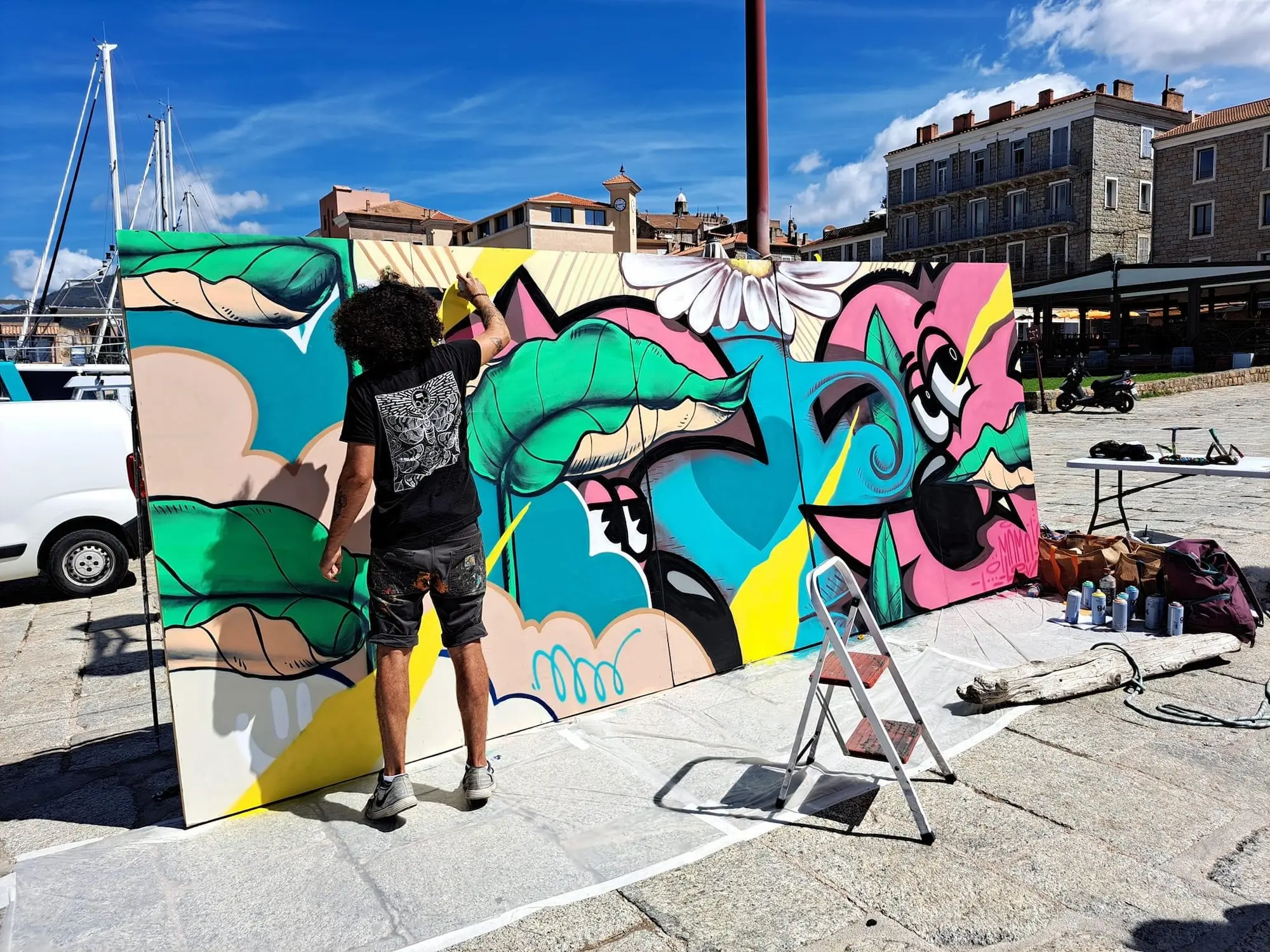 Live painting au chapiteau Artpoval, 2022 : l'artiste peignant la grande toile sur le port, escabeau et bombes au pied du panneau