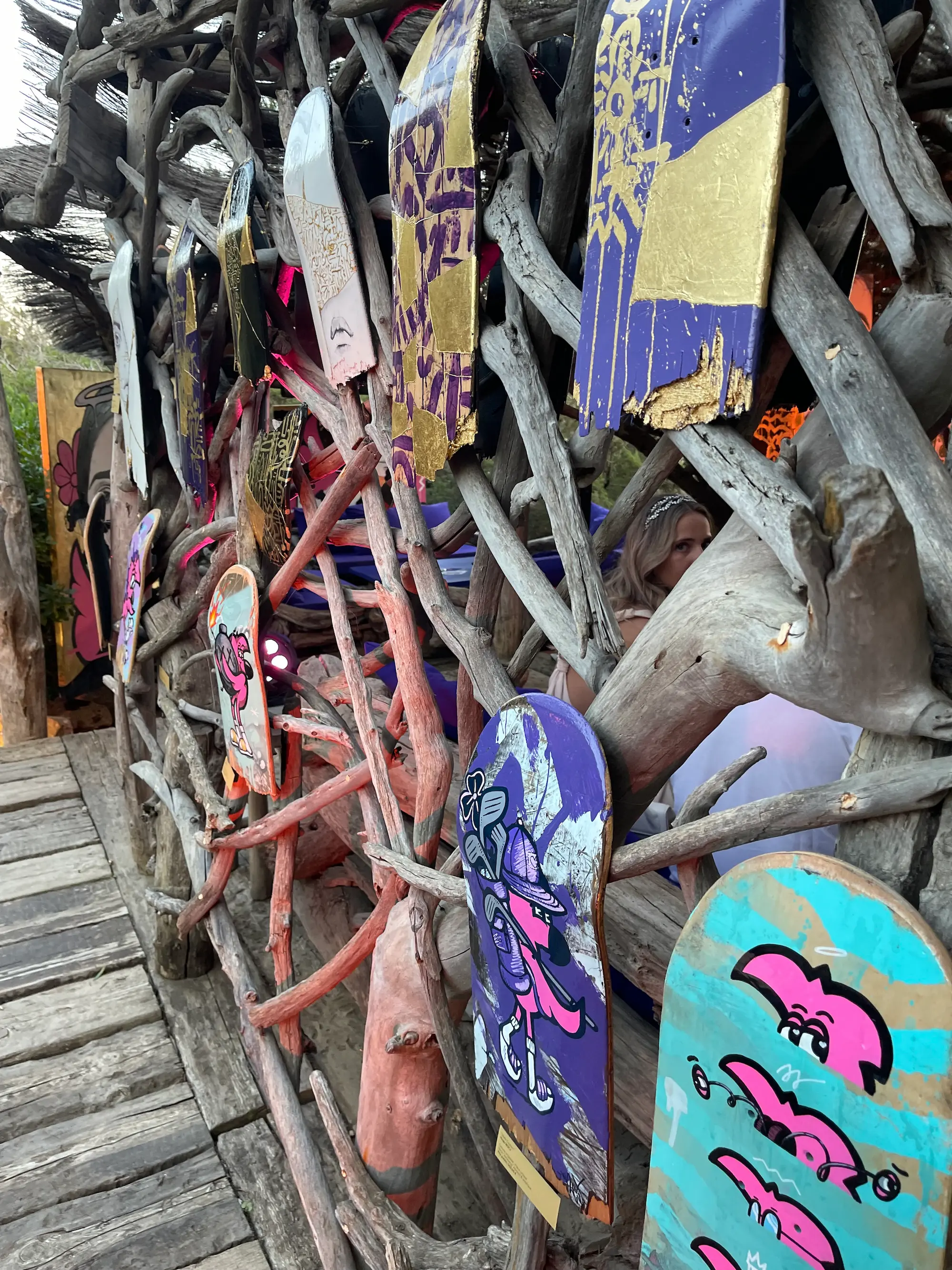 Exposition au Domaine de Murtoli, 2023 : plateaux de skate peints accrochés en série dans une structure de branches