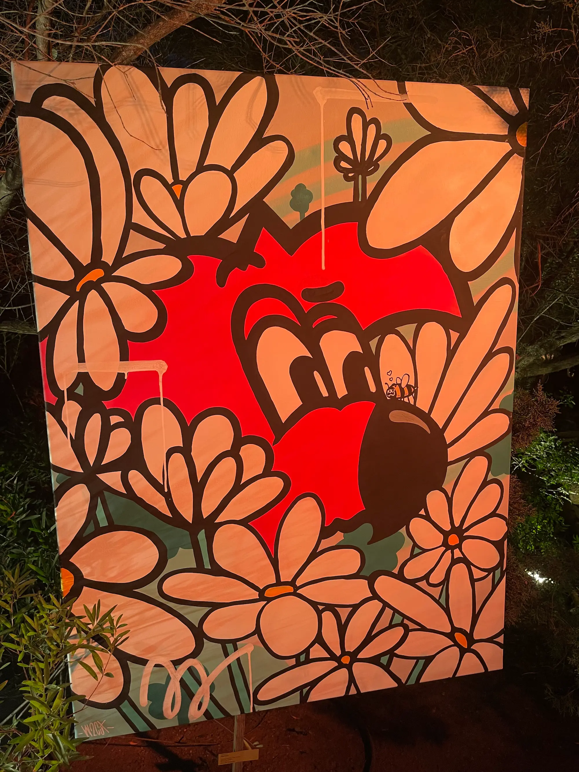 Exposition au Domaine de Murtoli, 2023 : toile éclairée de nuit, cœur rouge souriant entouré de grandes fleurs