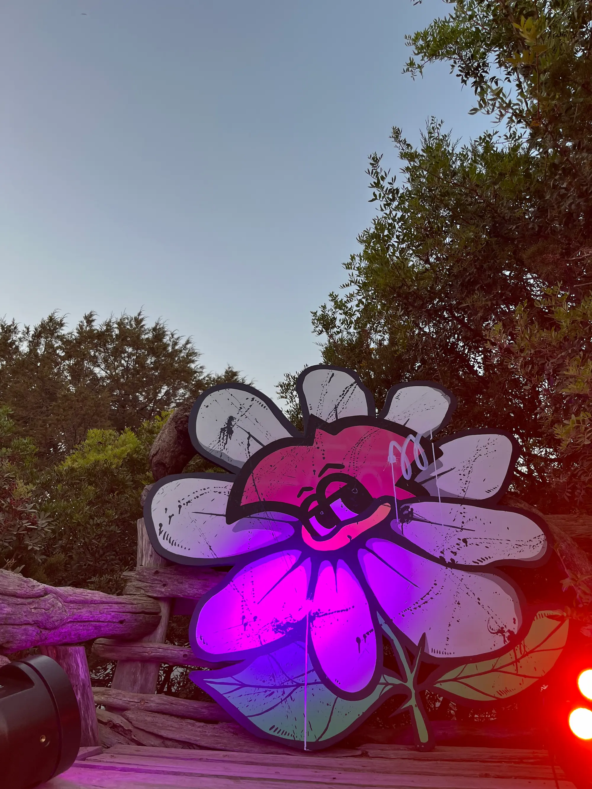Exposition au Domaine de Murtoli, 2023 : découpe en forme de fleur au visage de Roger le Flamant Rose, éclairée en violet au crépuscule