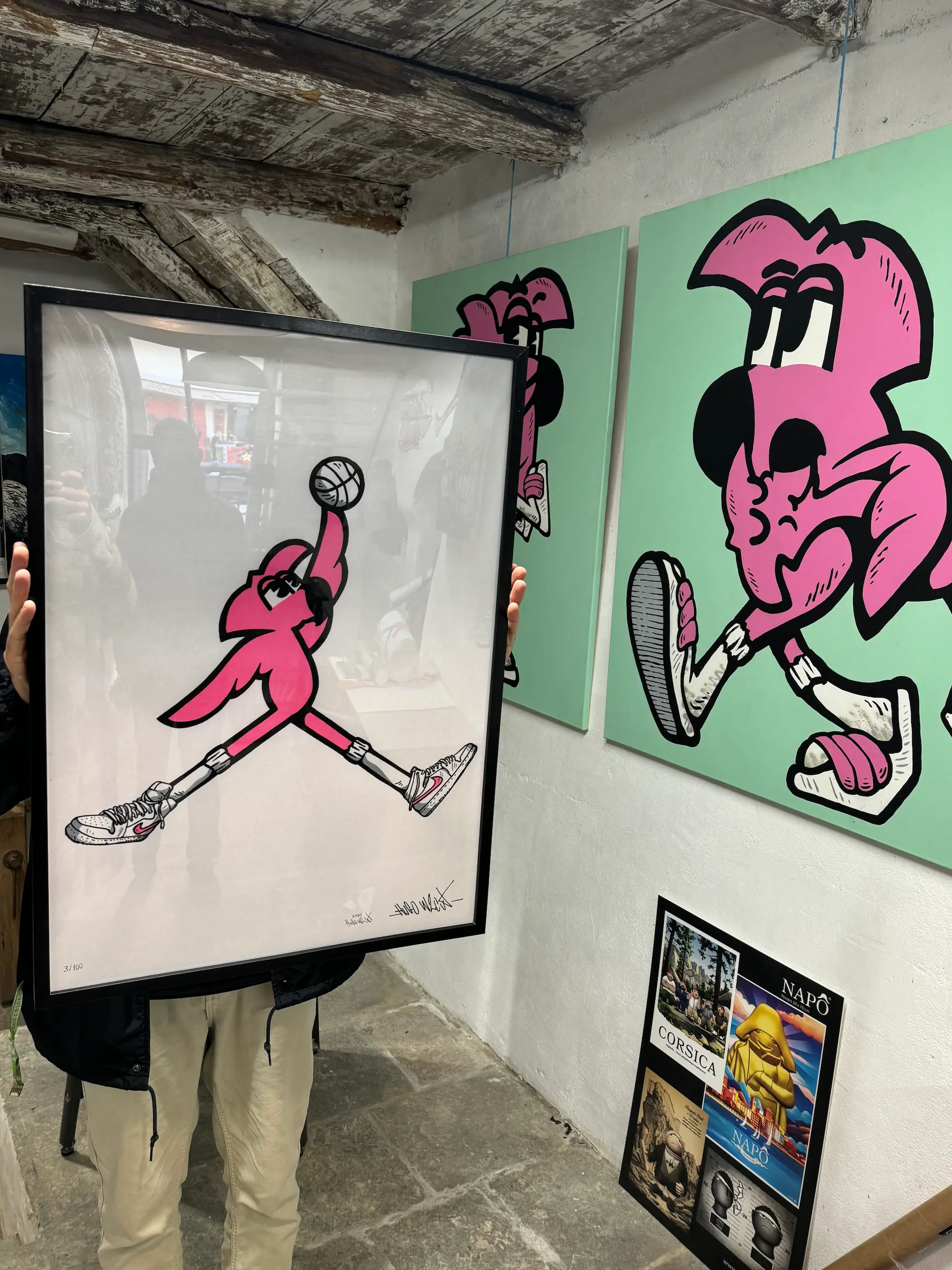 Exposition collective à la Capu Galerie, 2024 : tirage encadré de Roger le Flamant Rose en basketteur, tenu devant deux toiles vertes de Roger