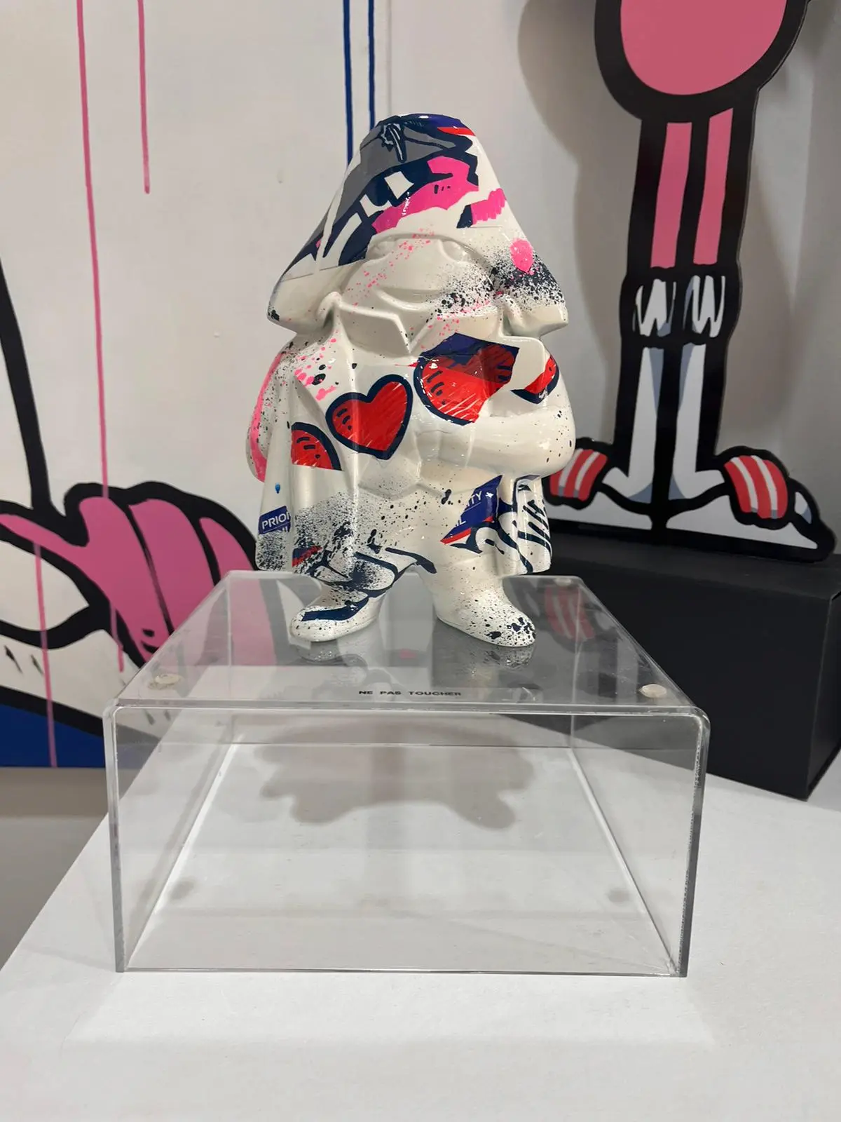 Exposition Contami, 2024 : sculpture blanche peinte de cœurs rouges et de motifs, posée sur un socle en plexiglas