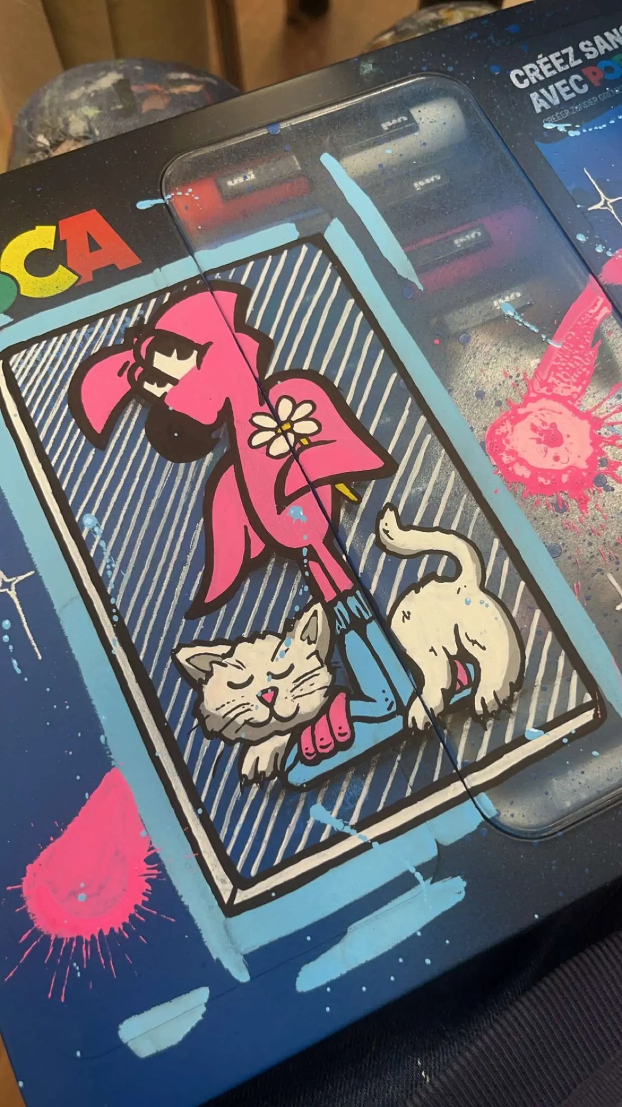 Collaboration Hugo W2CJ x Posca : coffret Posca peint, Roger le Flamant Rose tenant une fleur, un chat endormi à ses pieds