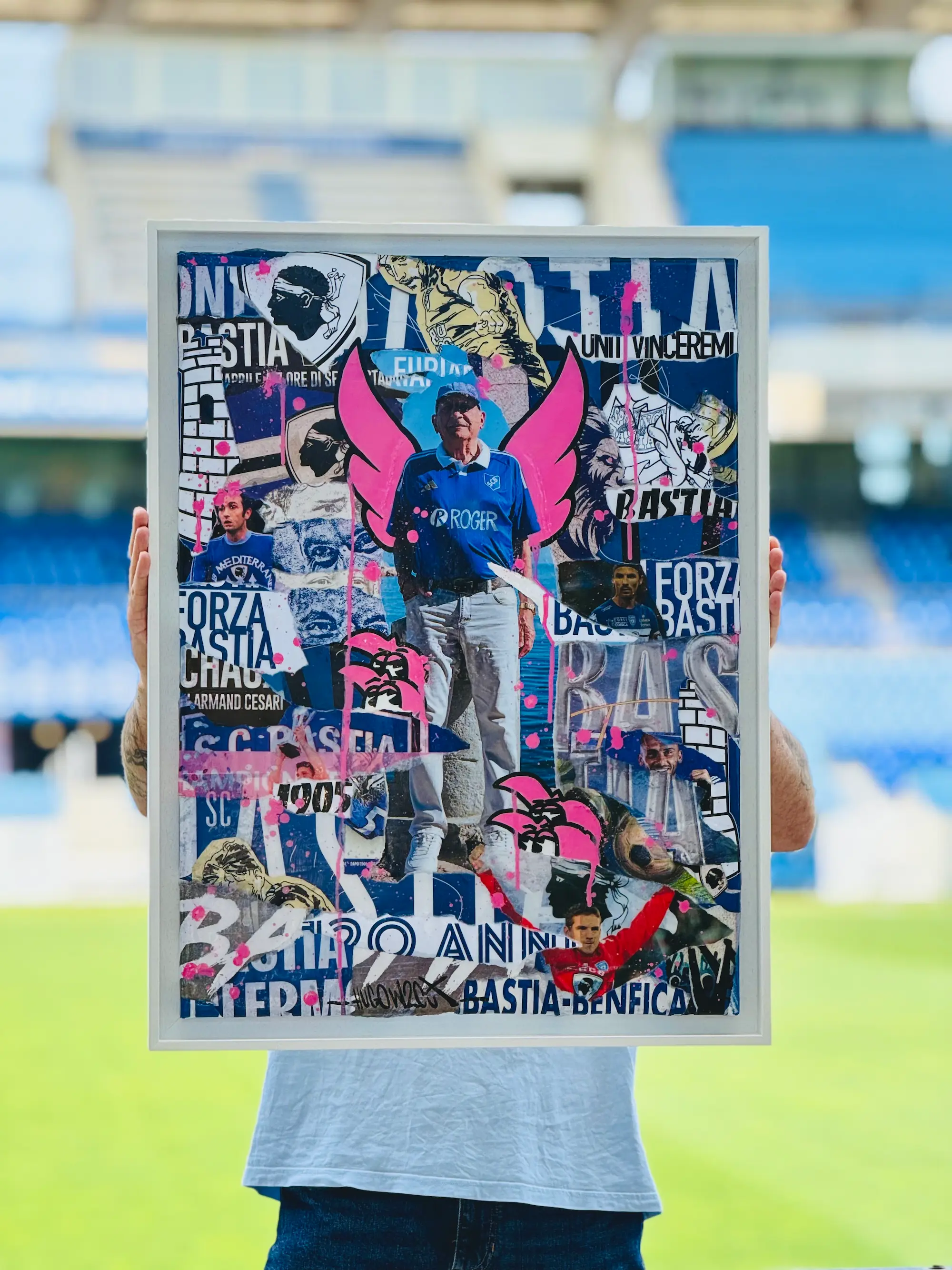 Collaboration Hugo W2CJ x Sporting Club de Bastia : tirage encadré aux couleurs du Sporting Club de Bastia, collage de photos du club et ailes roses, tenu sur la pelouse du stade