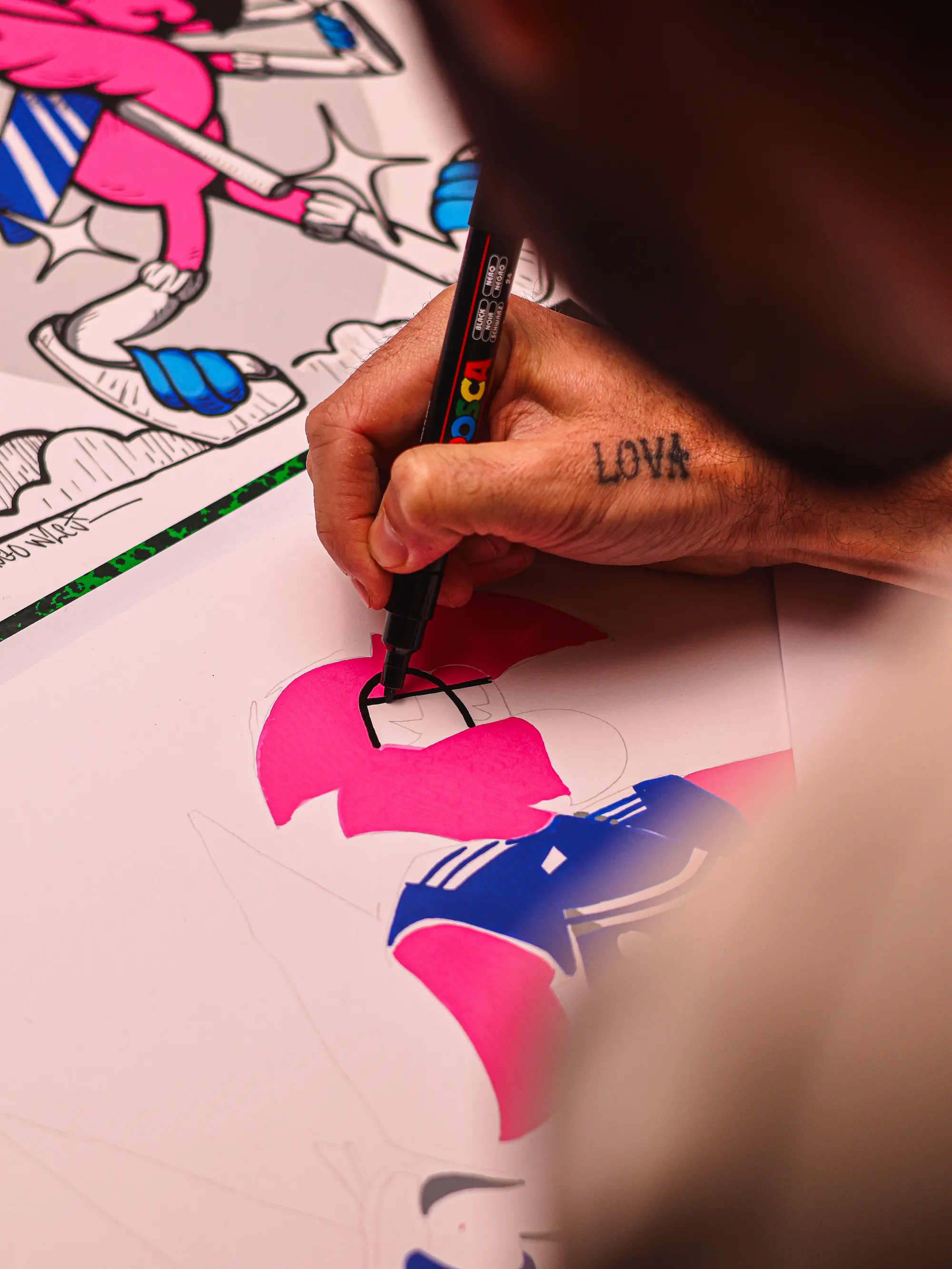 Collaboration Hugo W2CJ x Sporting Club de Bastia : gros plan sur la main de l'artiste coloriant au marqueur rose un dessin de Roger le Flamant Rose