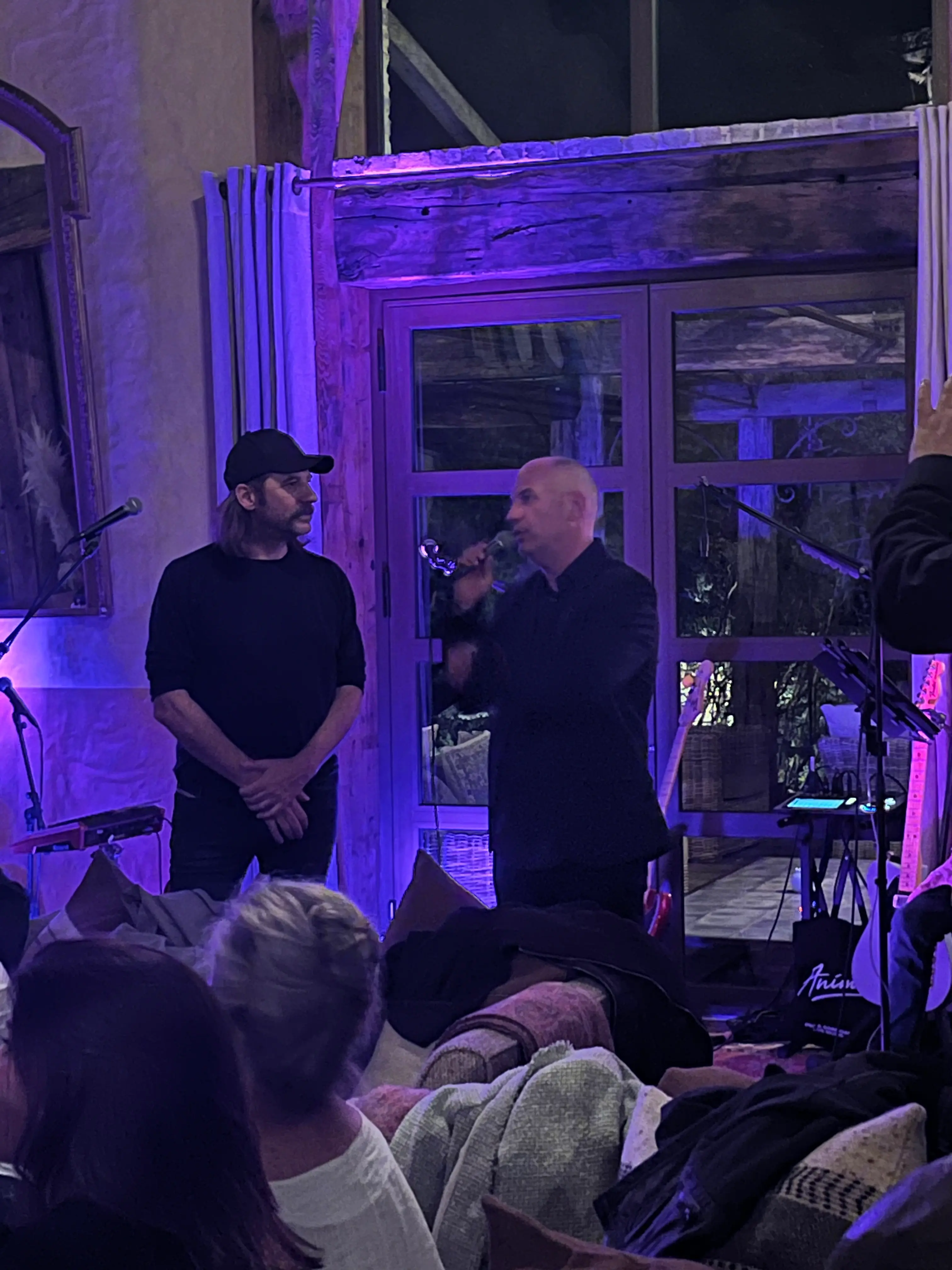 Fred Testot, parrain de l'édition 2024, et l'artiste Anto fils de Pop au micro sous un éclairage violet, soirée de vente caritative pour l'association Inseme au Domaine de Murtoli