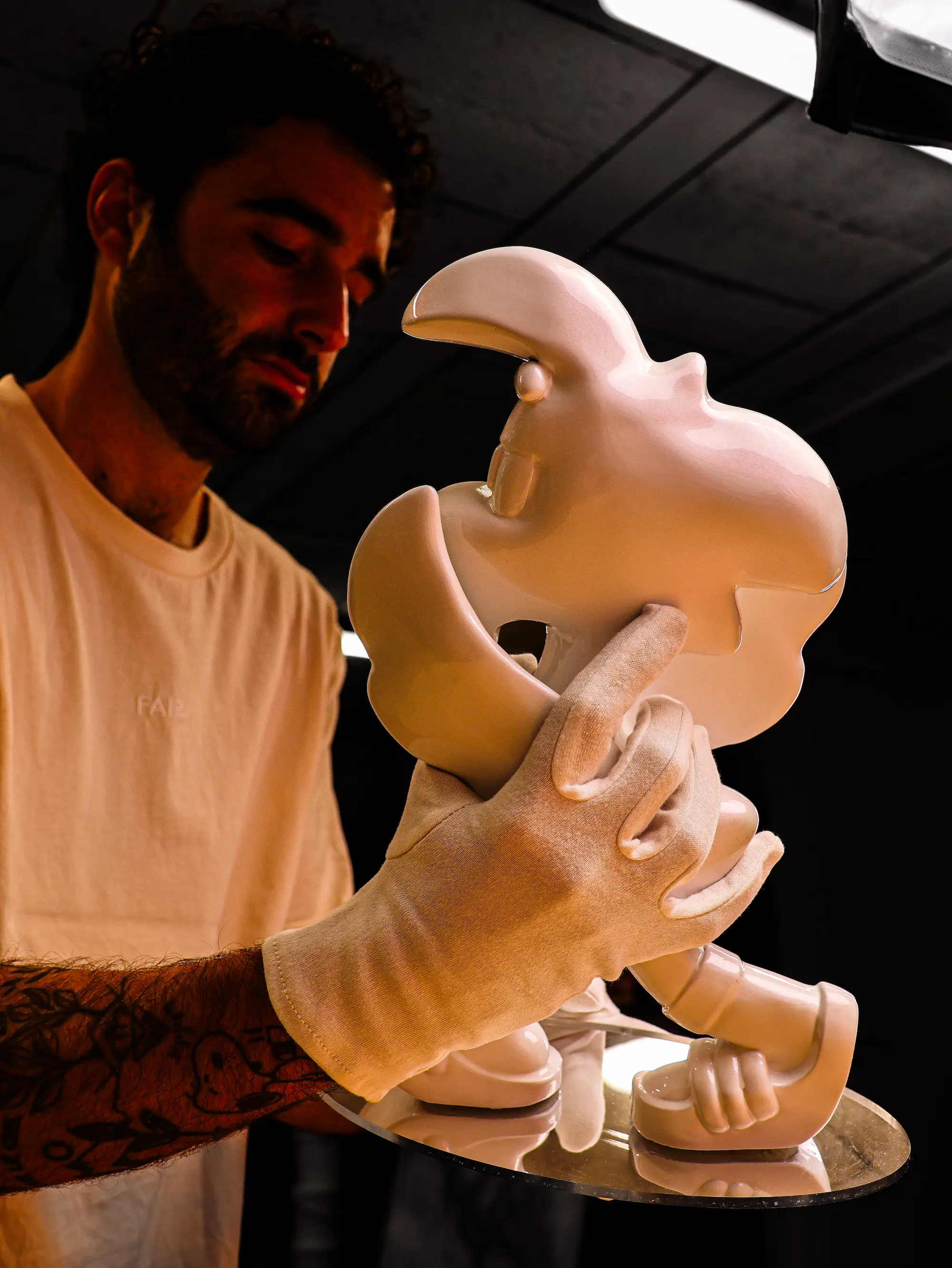Sculpture Roger le Flamant Rose n°2, Blanc nacré : tenue par l'artiste, mains gantées de blanc