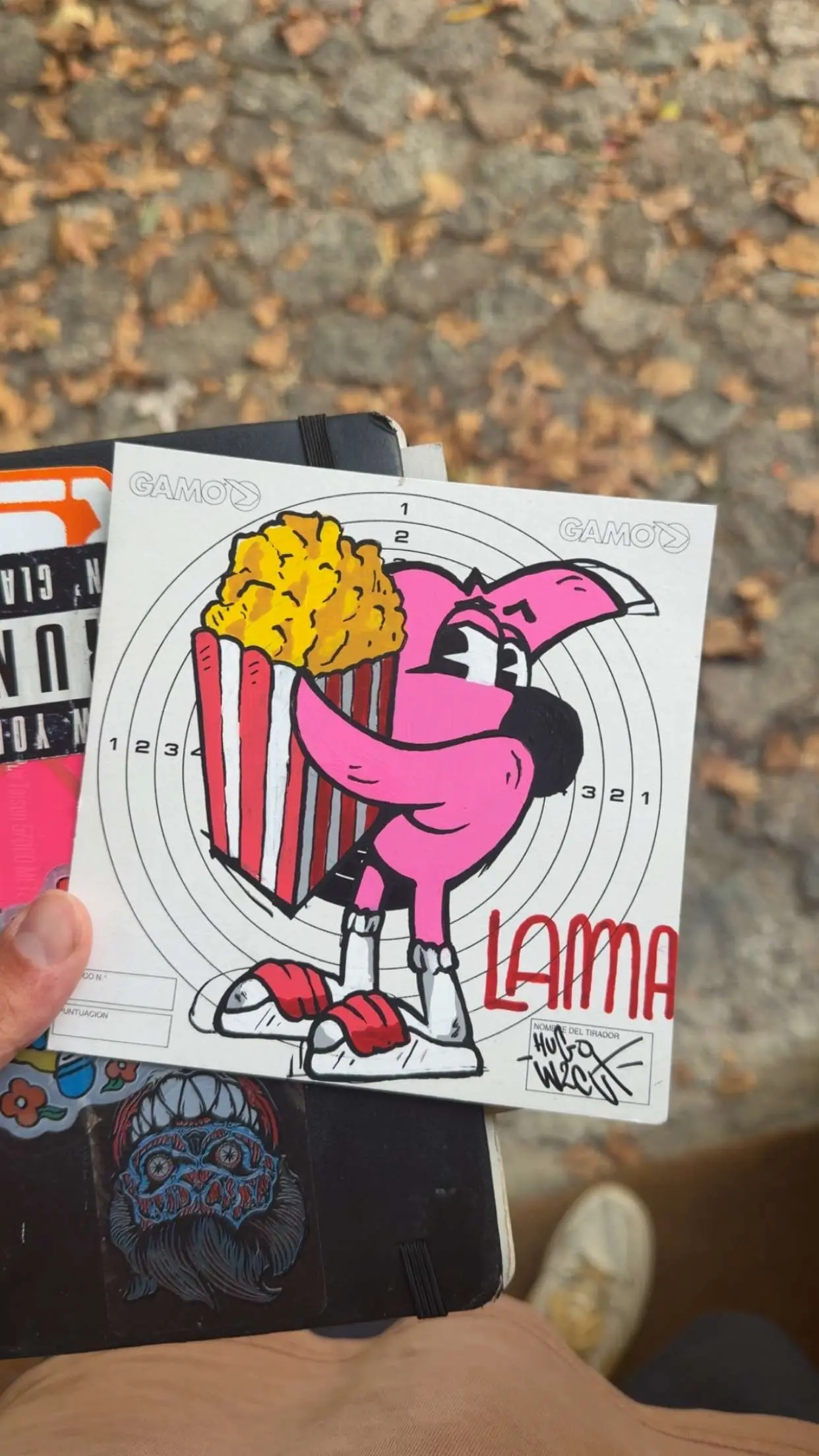 Dessin de Roger le Flamant Rose serrant un grand cornet de pop corn, signé Hugo W2CJ sur une cible de tir, Festival du film de Lama