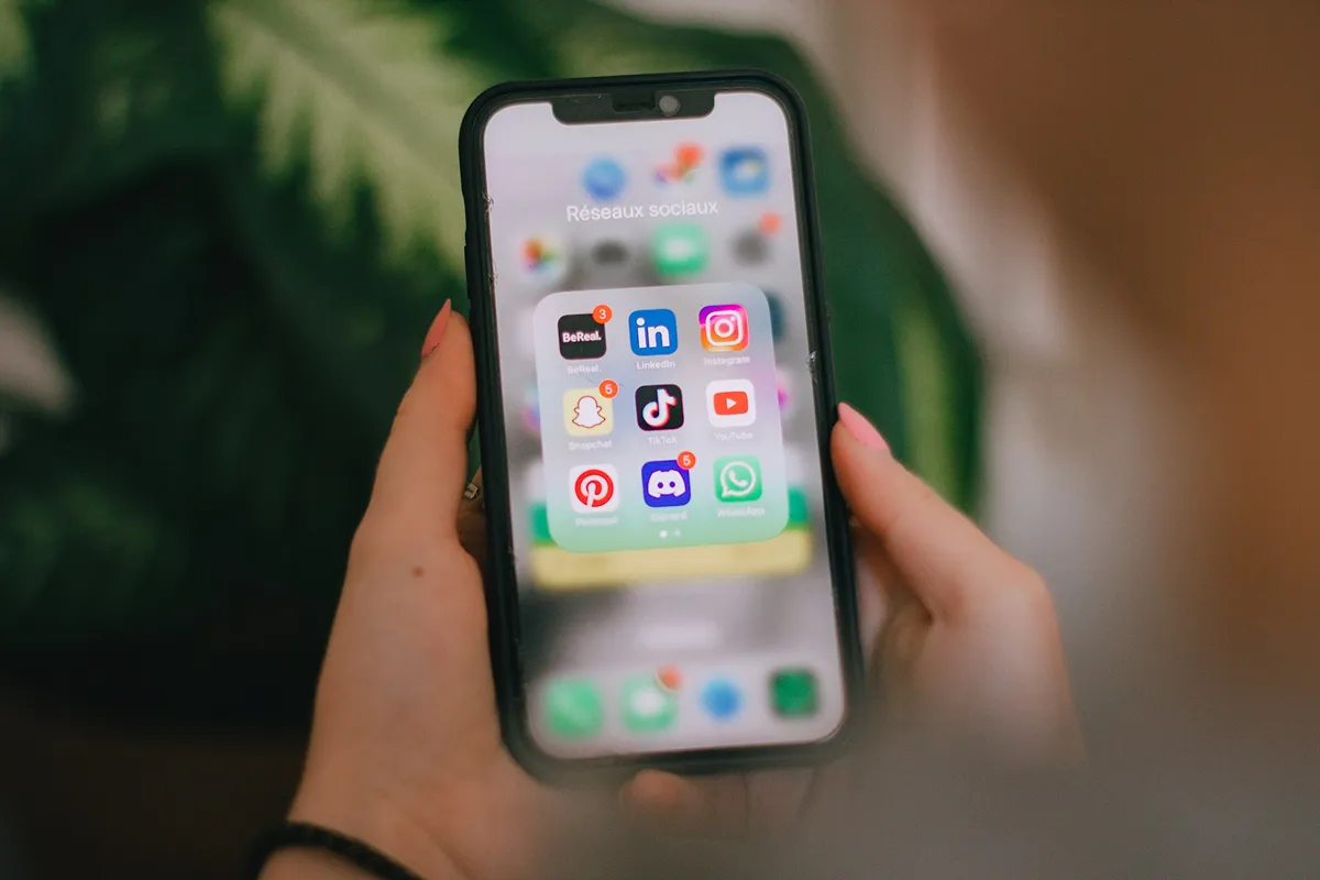 Hand hält ein Smartphone mit geöffneten Social-Media-Apps