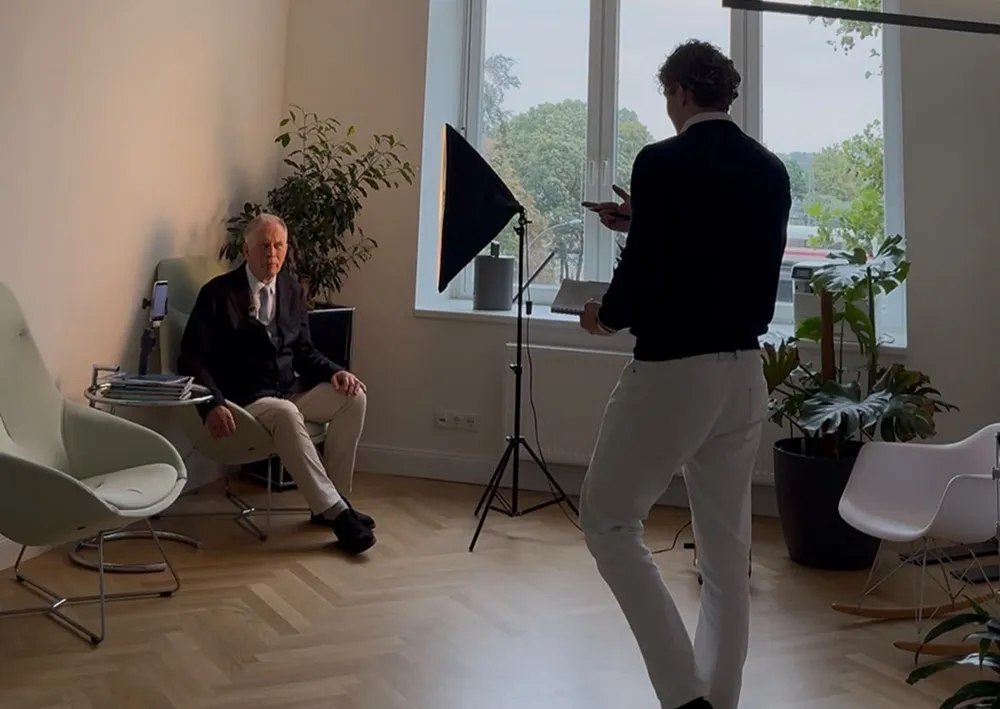 Tom Agge filmt einen Kunden am Fenster bei Tageslicht