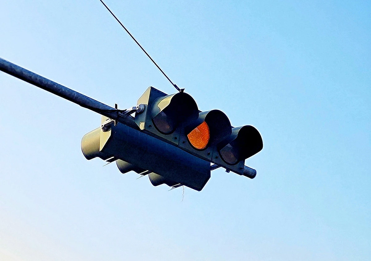 Image of a traffic light on red against a bright, sunny, blue sky.