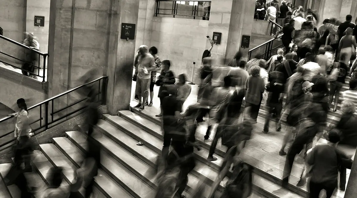 Stockimage of people in motion, taken with motion blur, inside a busy hall of stairs.