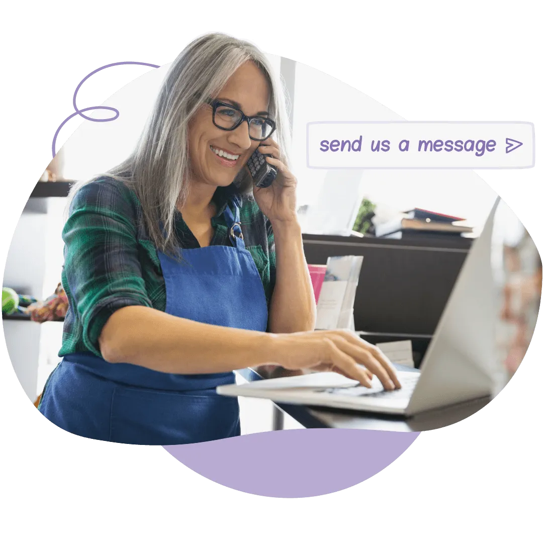 Pet business owner on a phone call while typing on a laptop, with a chat bubble reading send us a message.