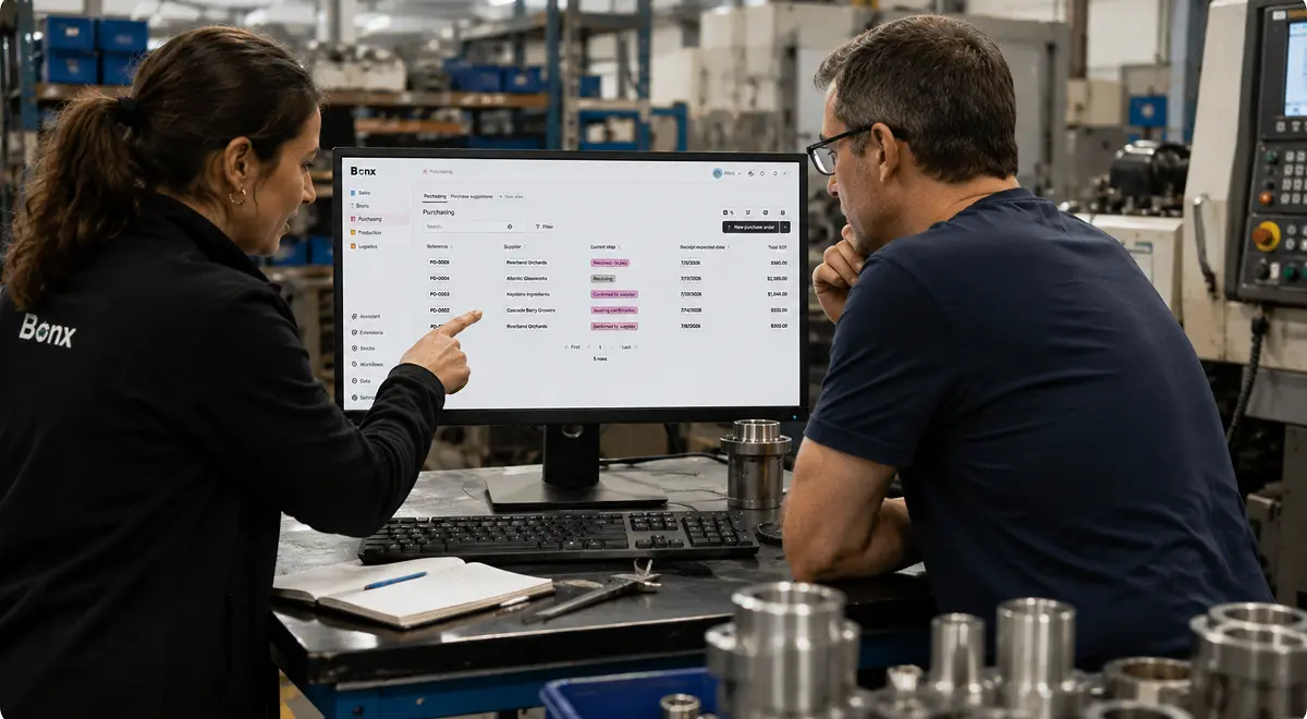 Bonx team member pointing at an on-screen order list next to a machinist at his workstation during rollout.