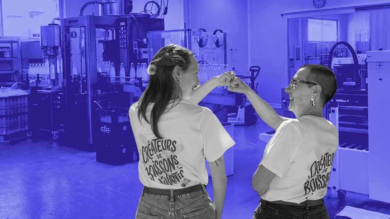 Due membri del team L'Atelier du Ferment battono il pugno davanti alla linea di imbottigliamento del kefir, con le magliette «Créateurs de boissons vivantes».