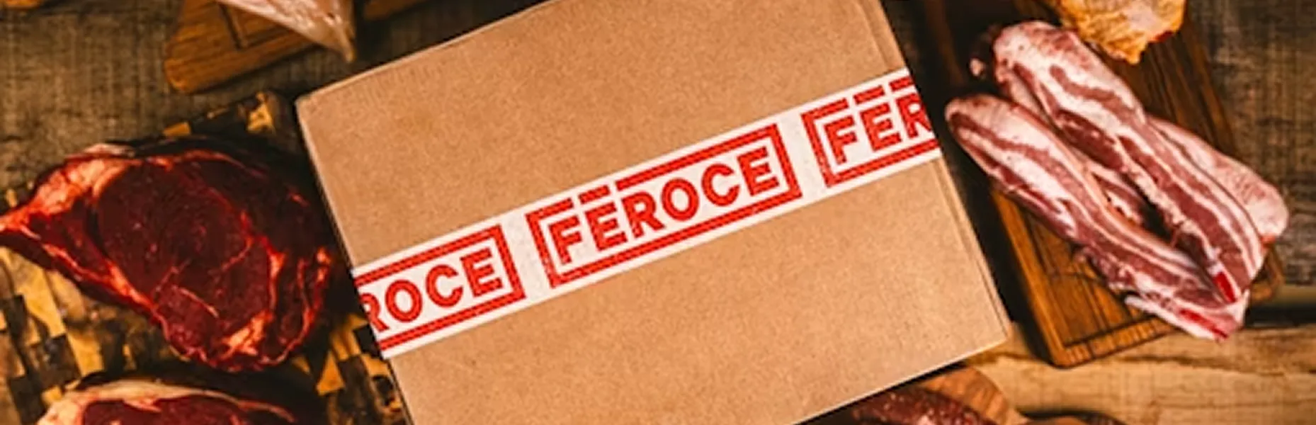 A Féroce branded box beside cuts of steak and bacon on a wooden board.