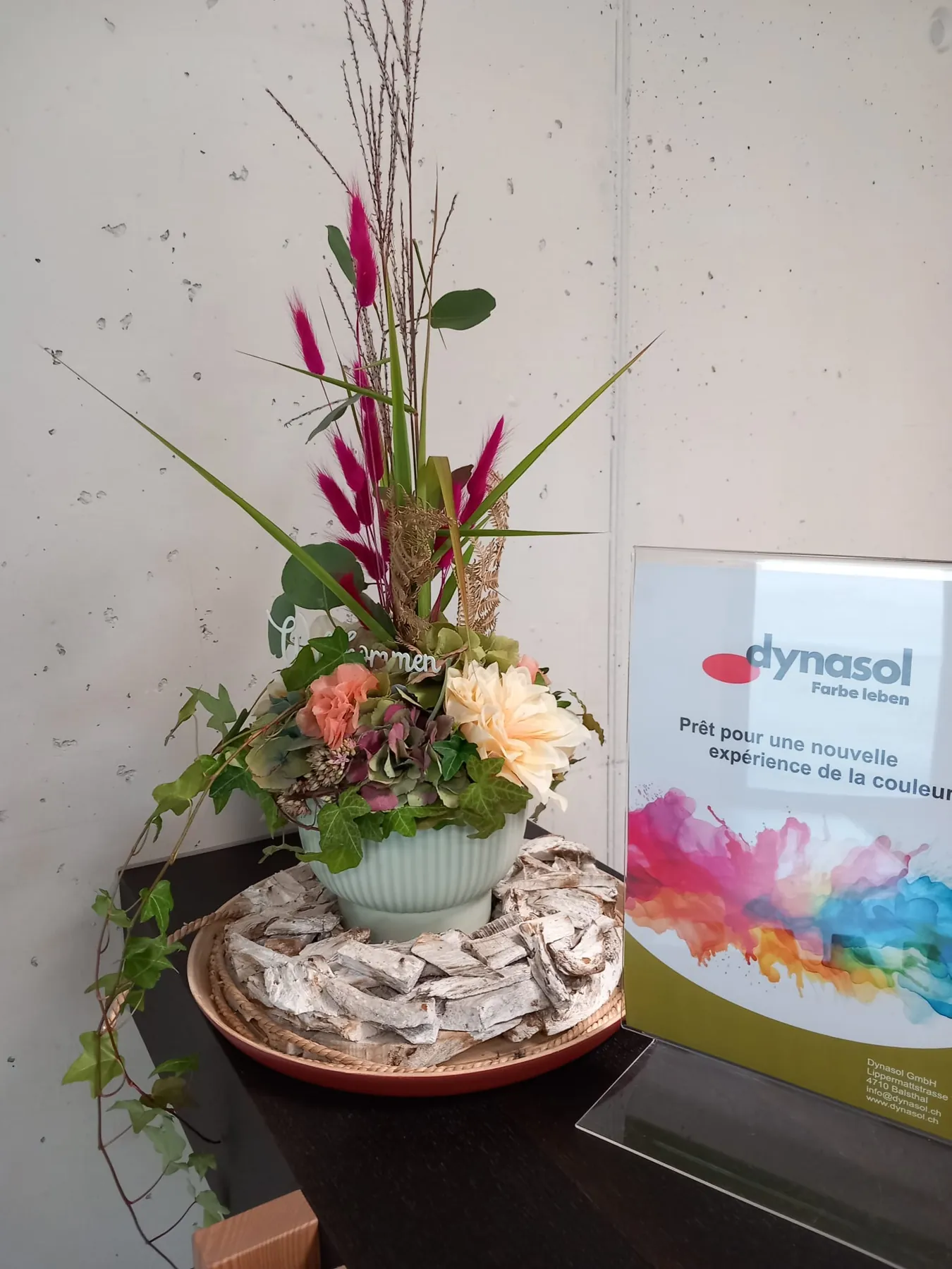 Florales Arrangement mit Rosen und Gräsern auf einem Empfangstresen