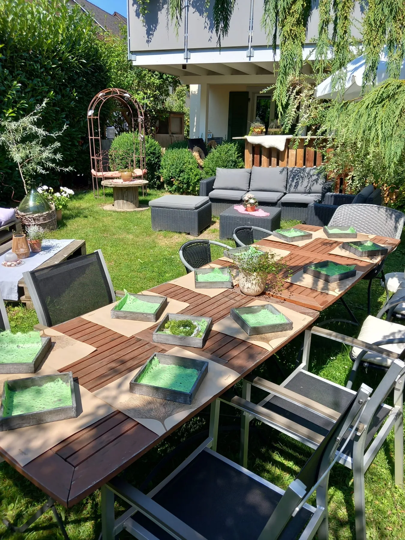 Vorbereiteter Holztisch mit grünen Werkstücken im Garten von Blumen Vision